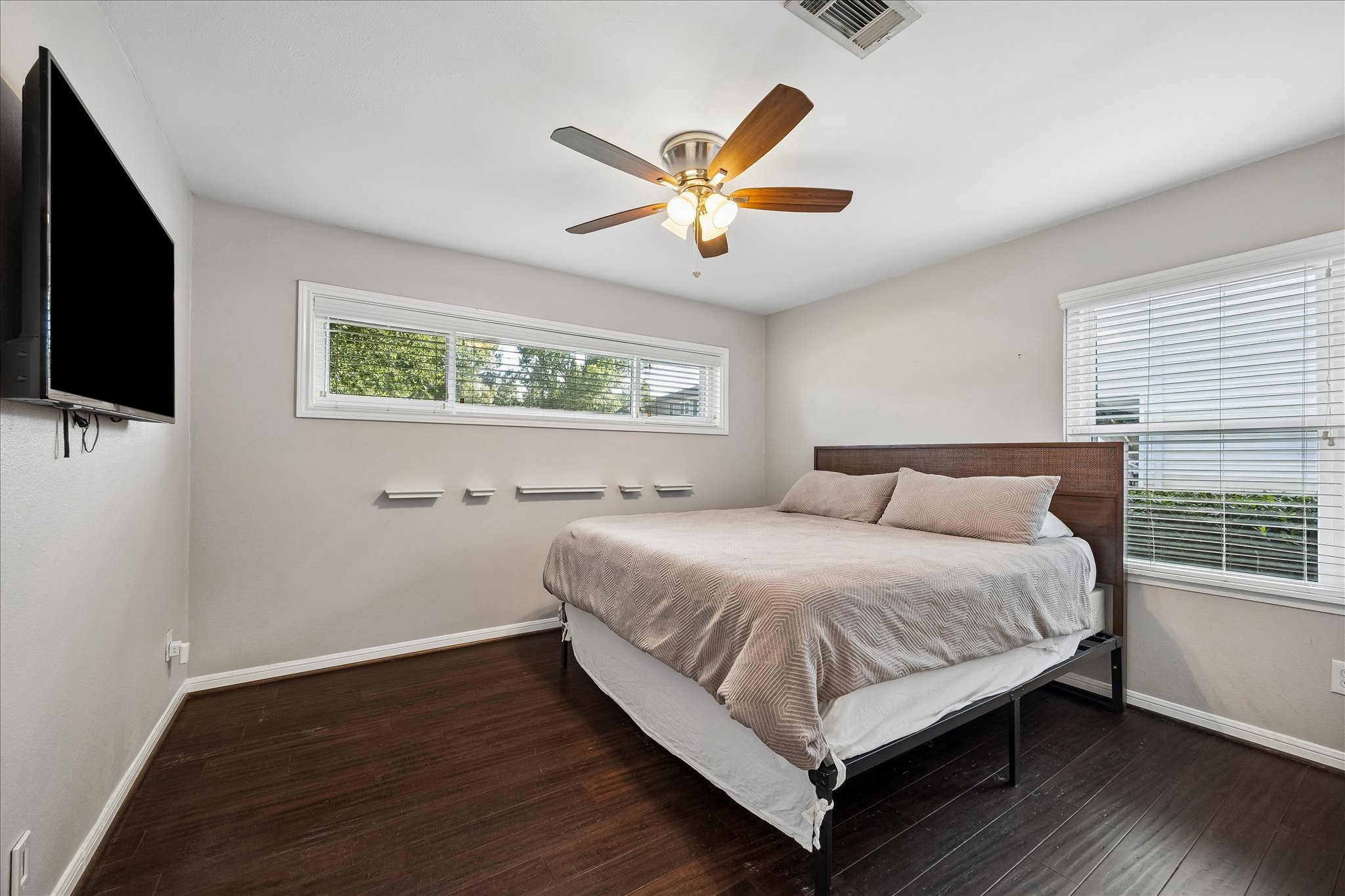 Oversized windows fill this secondary bedroom with natural light, creating a bright and inviting retreat for family or guests. Clean lines, warm flooring, and a flexible layout make the space equally suited for a bedroom, nursery, or home office.