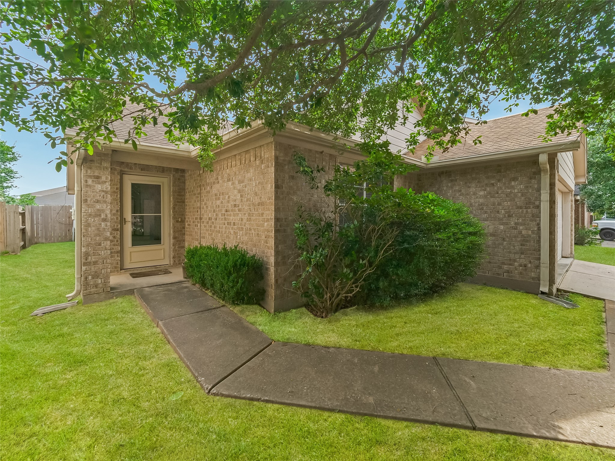 Side exterior view house featuring front entrance, green lawn, and established landscaping.