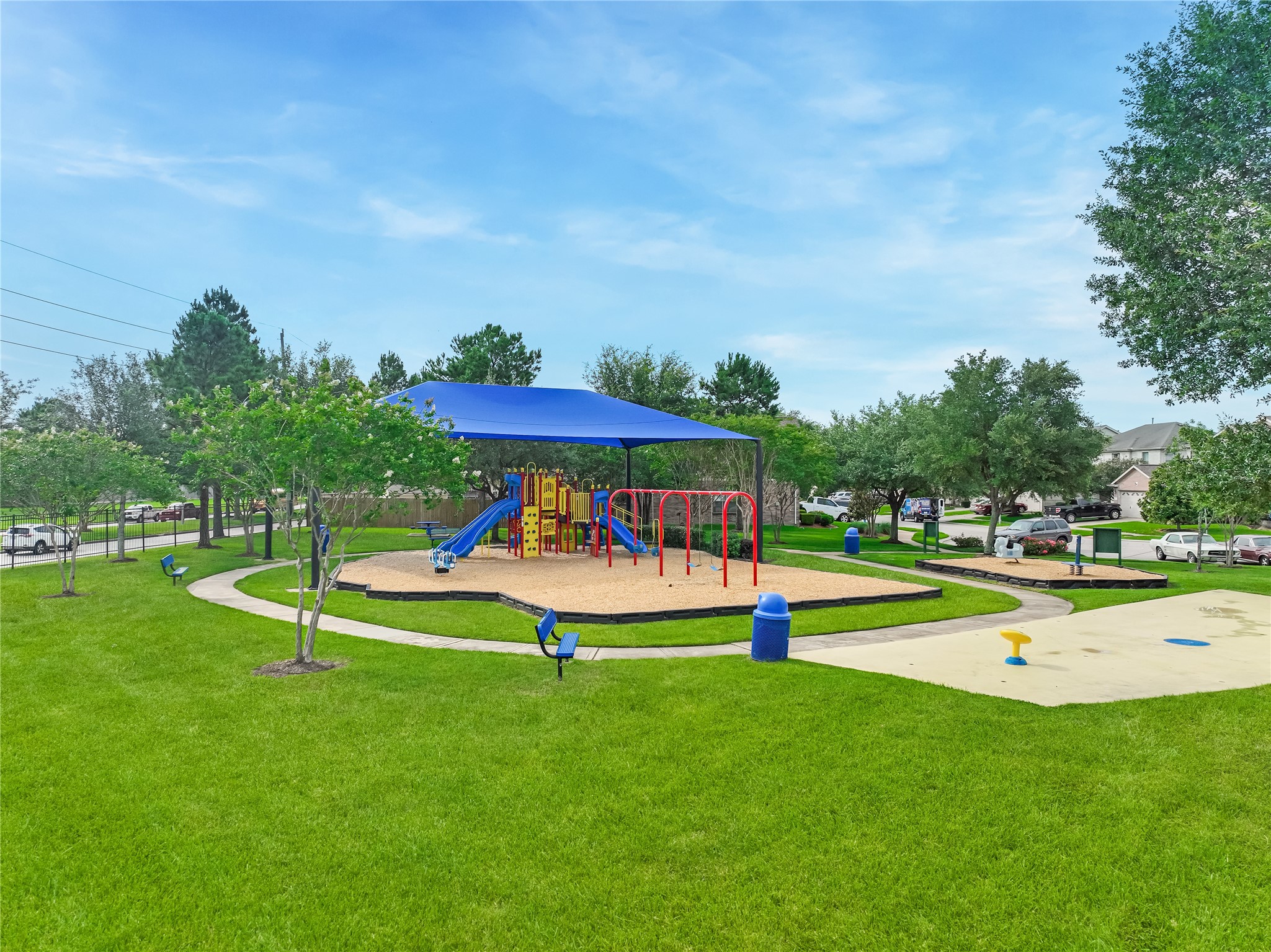Wide exterior view of the neighborhood amenities highlighting the playground, splash-pad, and surrounding greenery.