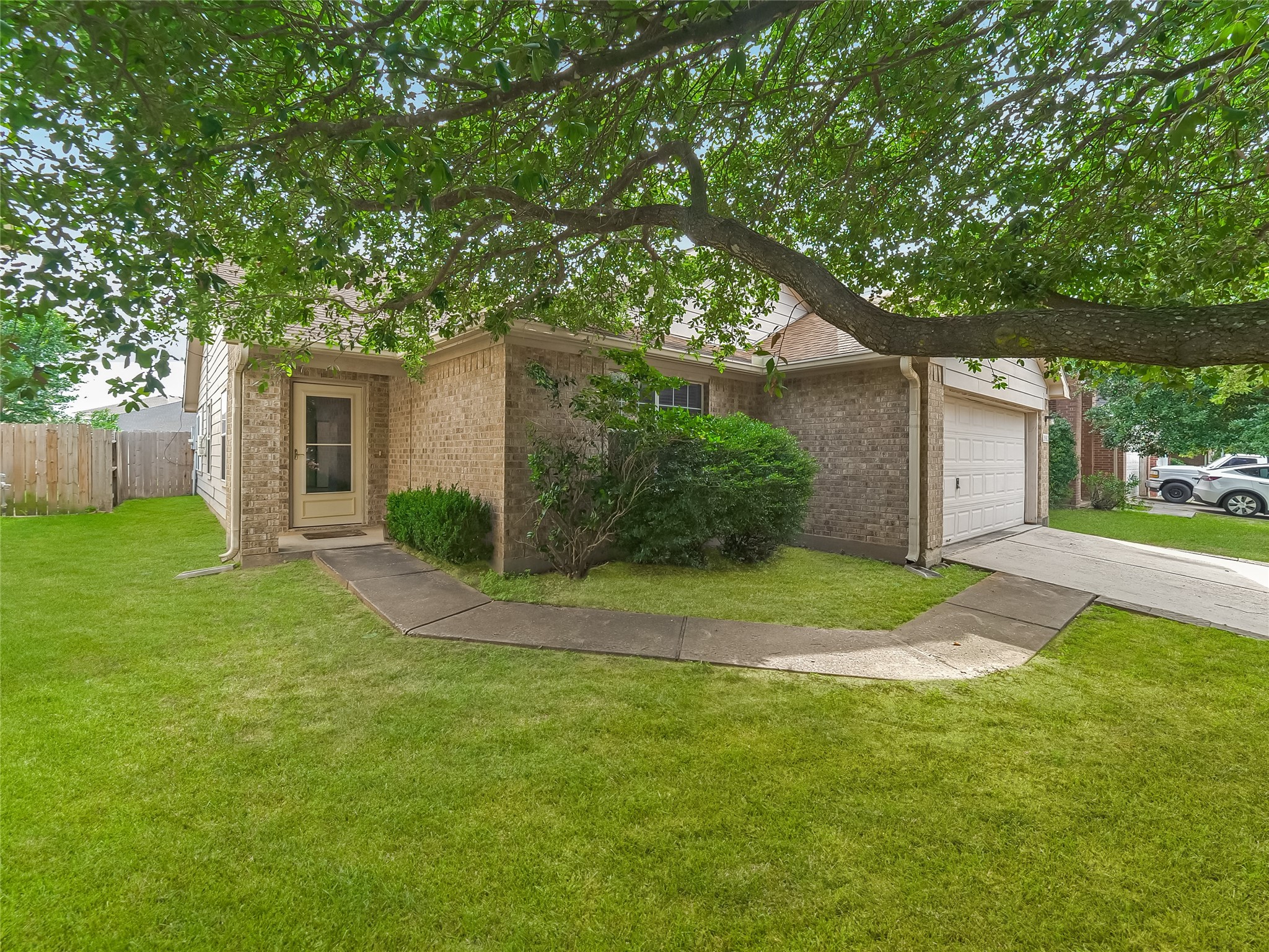 Exterior view of the home with a covered entryway, mature trees, and a landscaped yard.