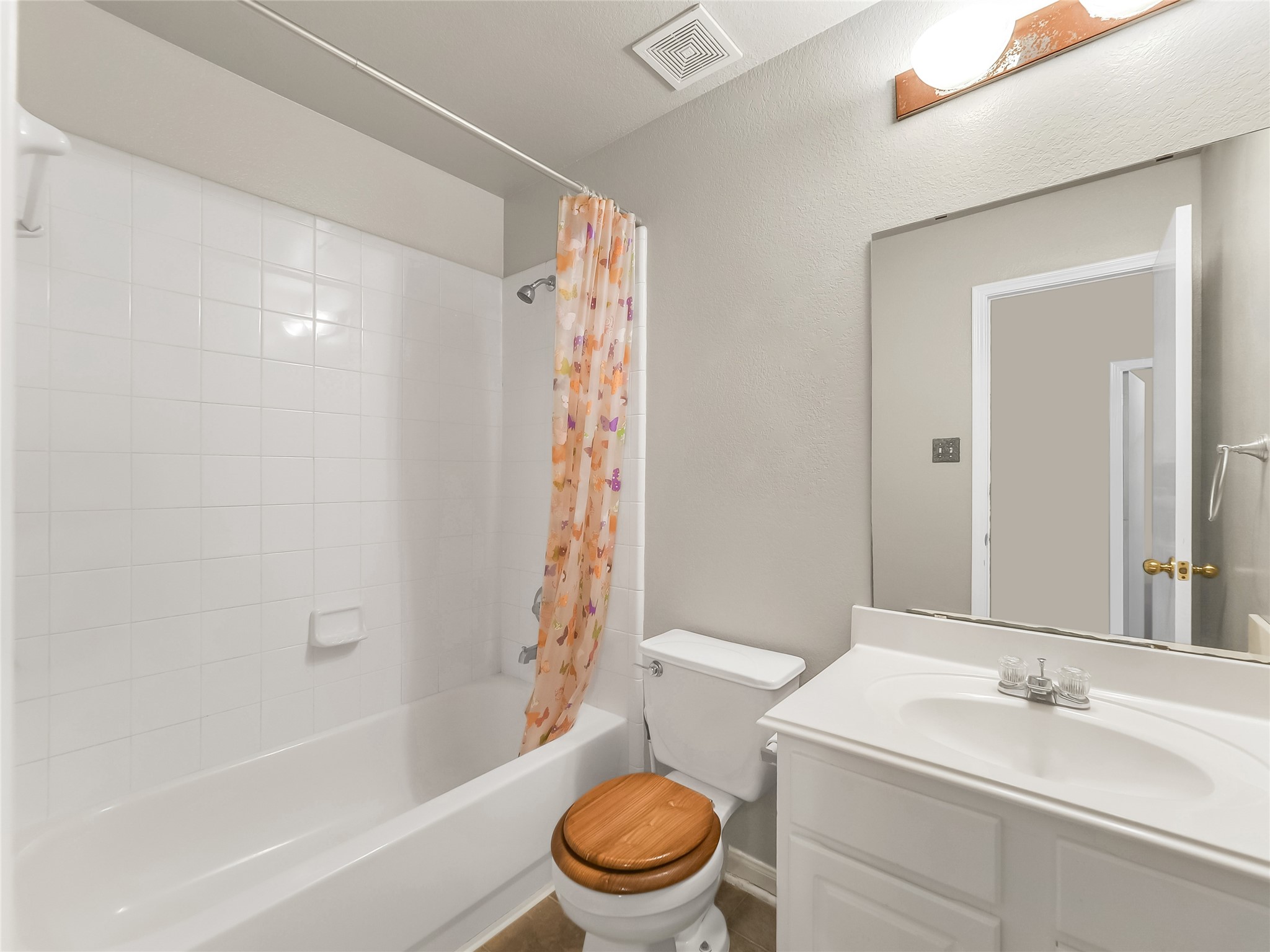 Bathroom with a bathtub and shower combination, tiled walls, and a vanity area.