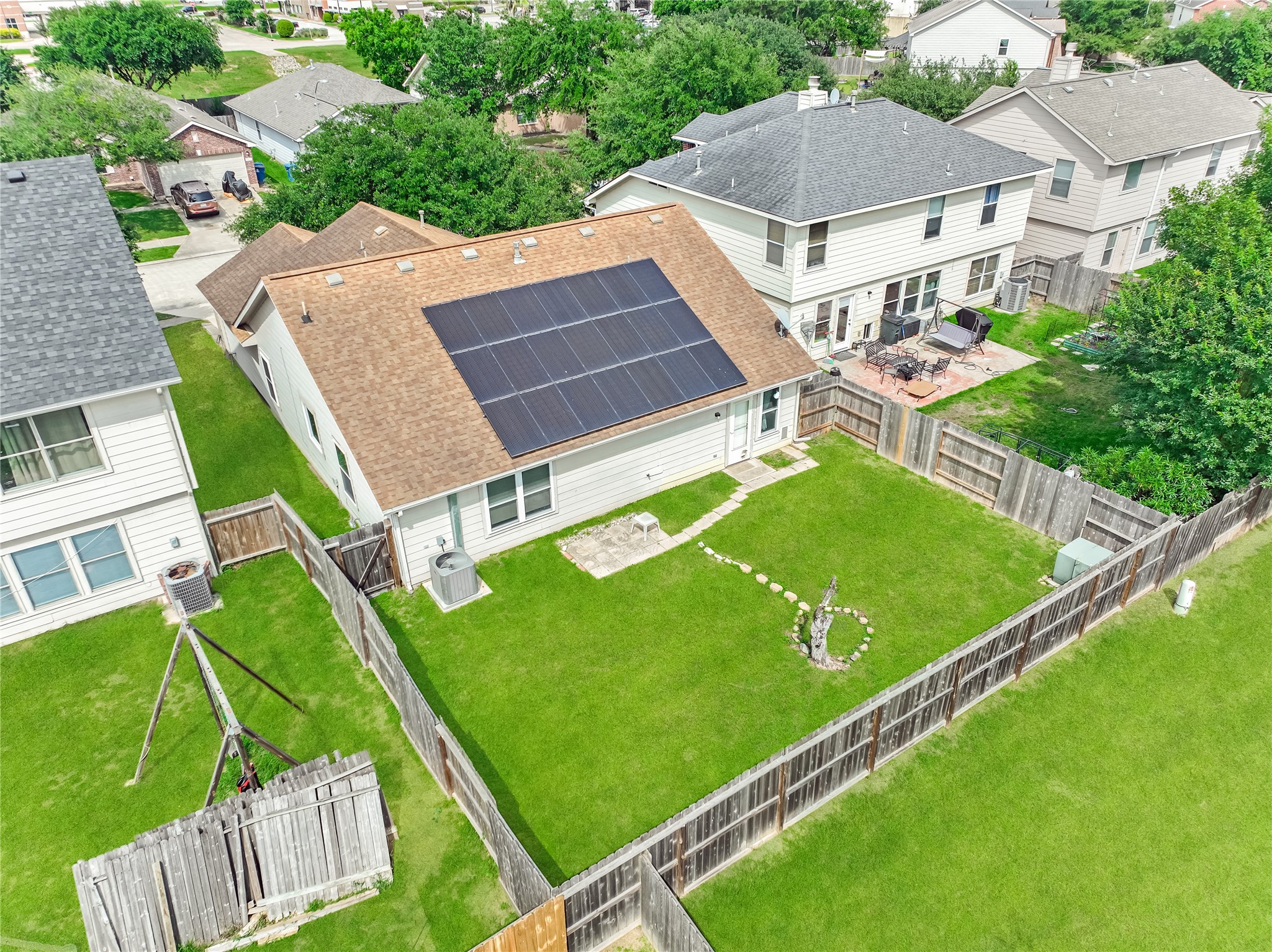 Aerial view of the property showing the house, backyard, surrounding homes, and nearby streets.