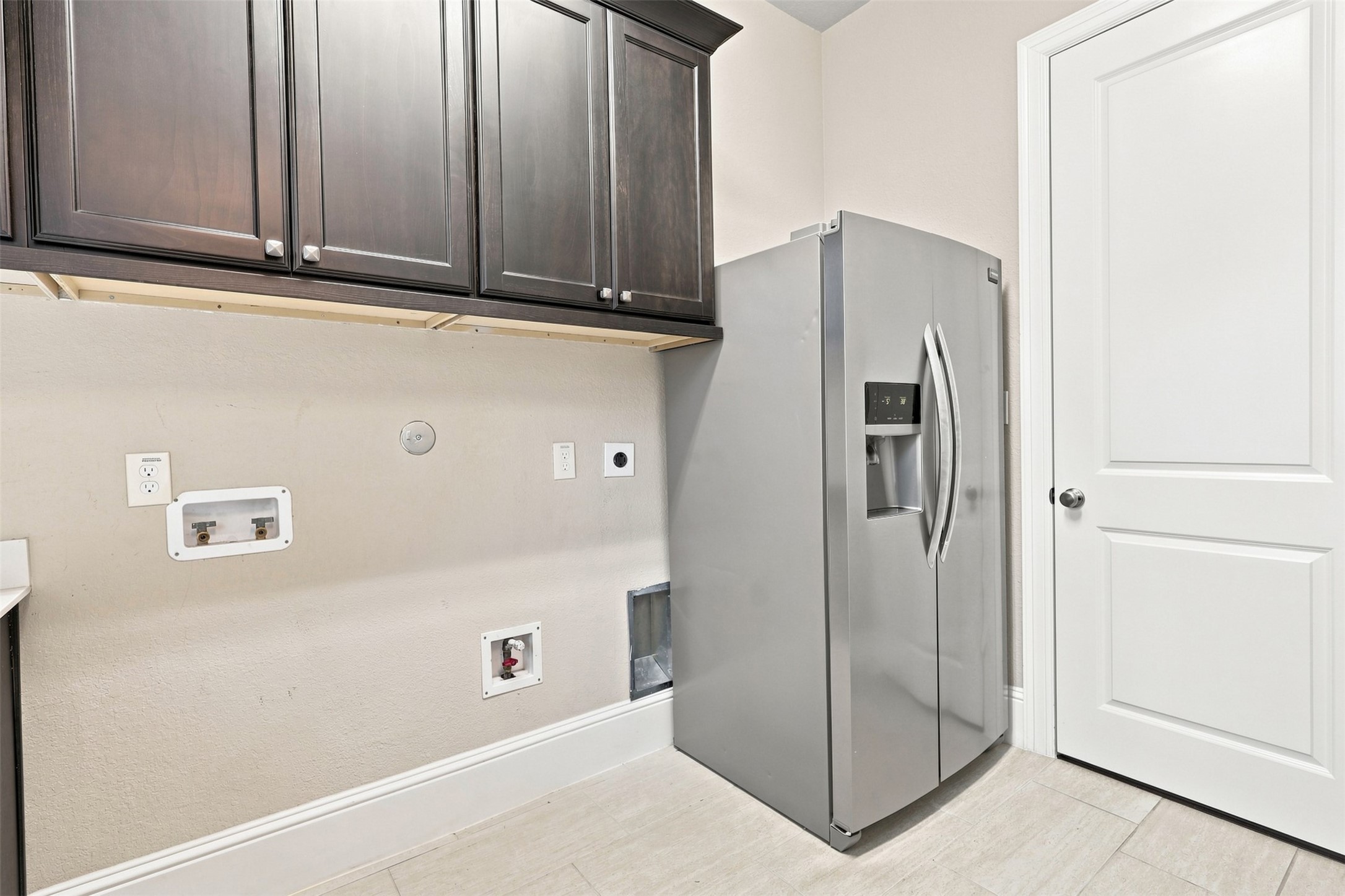 Spacious utility room with additional cabinetry and a full-size refrigerator.