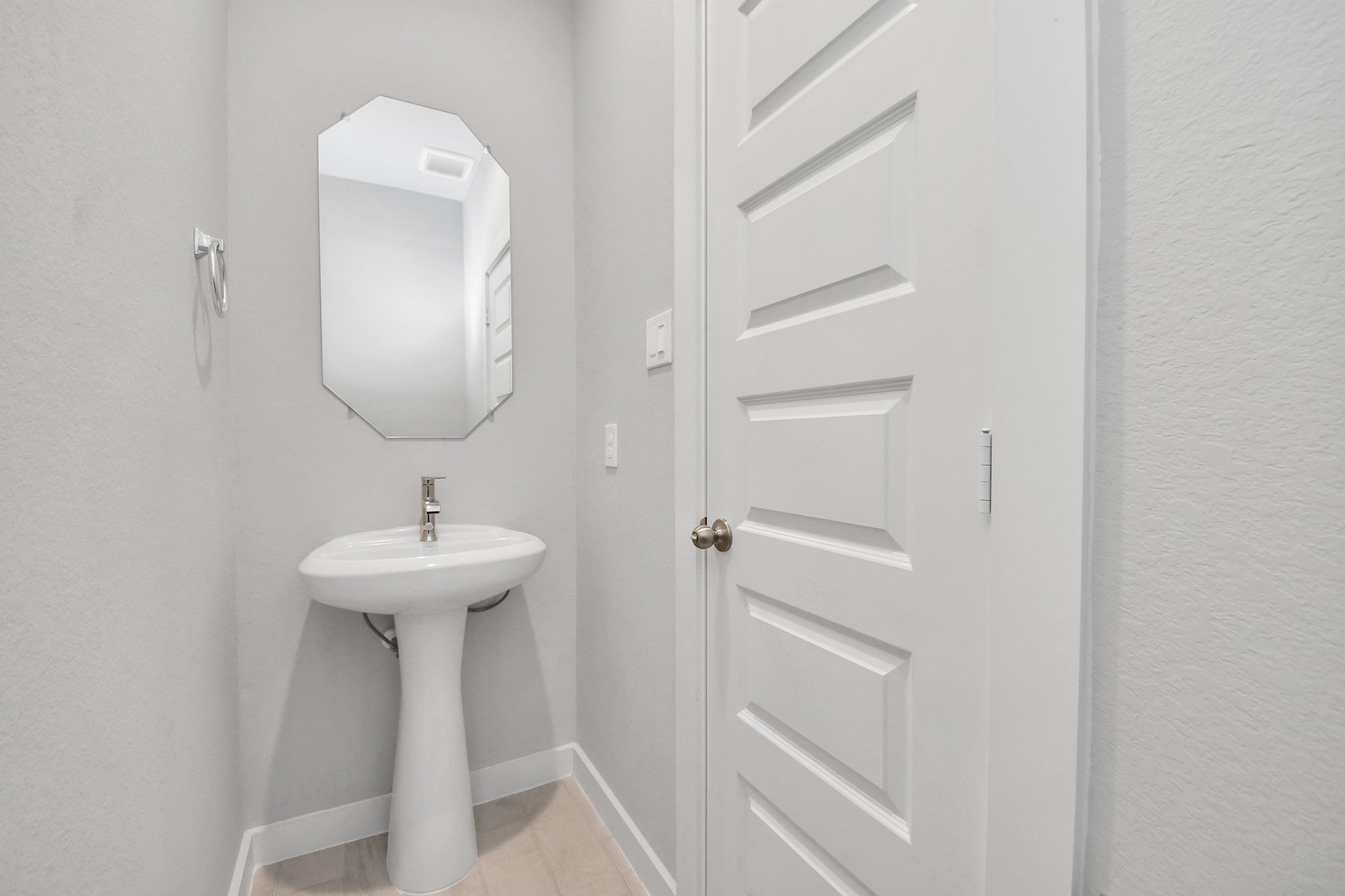This half bathroom features a stylish pedestal sink, modern hardware, and bright recessed lighting, creating a sleek and inviting space. Sample photo of completed home with similar floor plan. Actual colors and selections may vary.