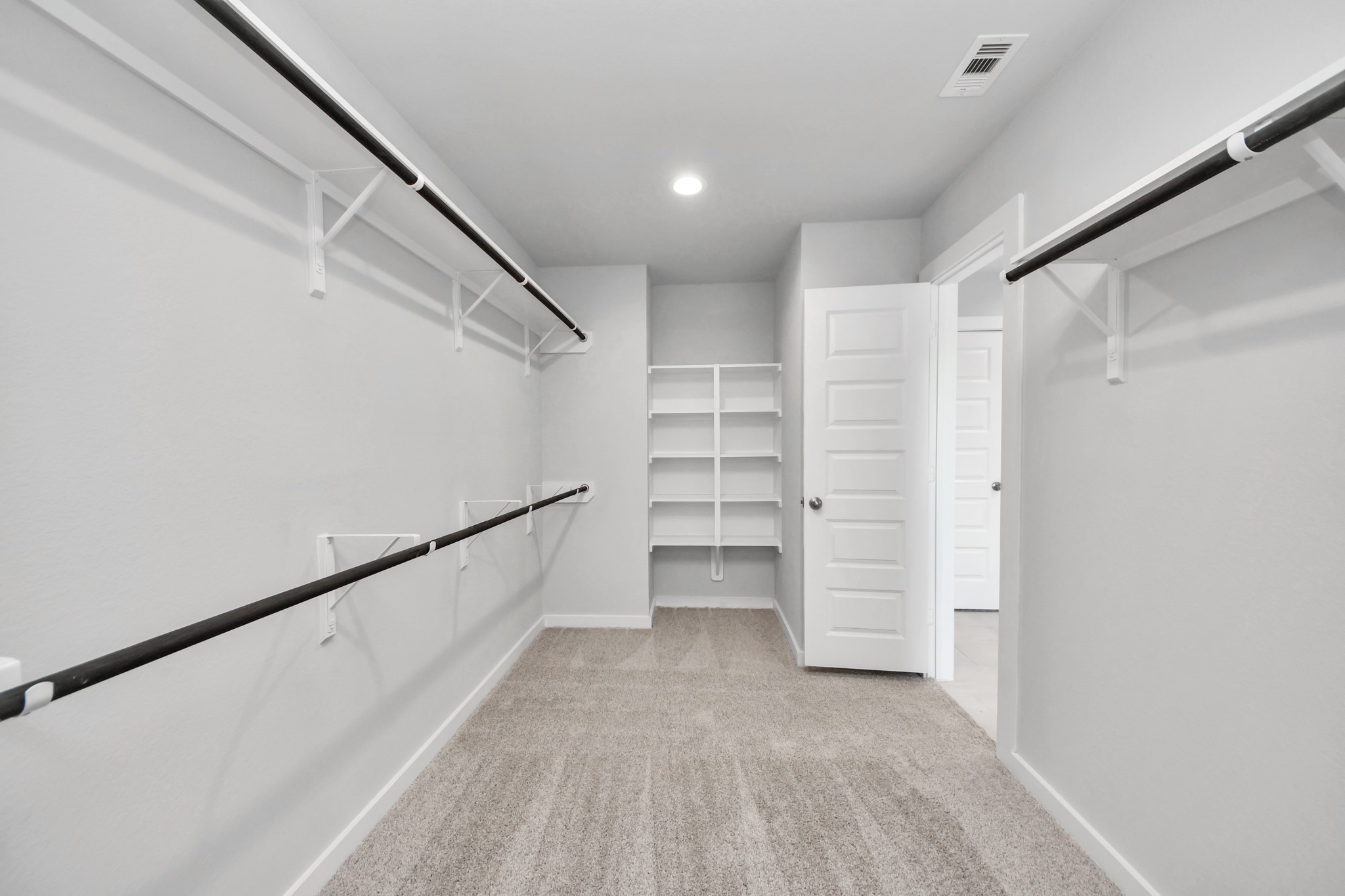 Walk-in closet that epitomizes luxury and practicality. This generously sized space features built-in shelving, offering abundant room for impeccable organization. High ceilings and recessed lighting create a bright and welcoming ambiance. Sample photo of completed home with similar floor plan. Actual colors and selections may vary.