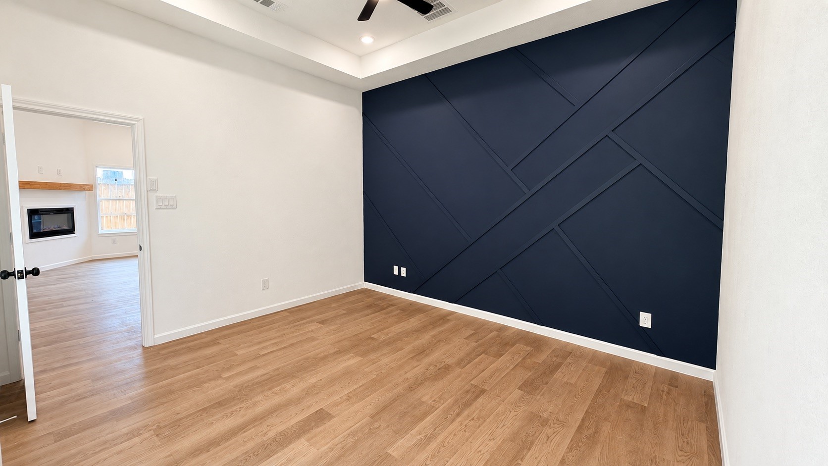 Bright primary bedroom featuring custom accent wall & durable vinly plank flooring