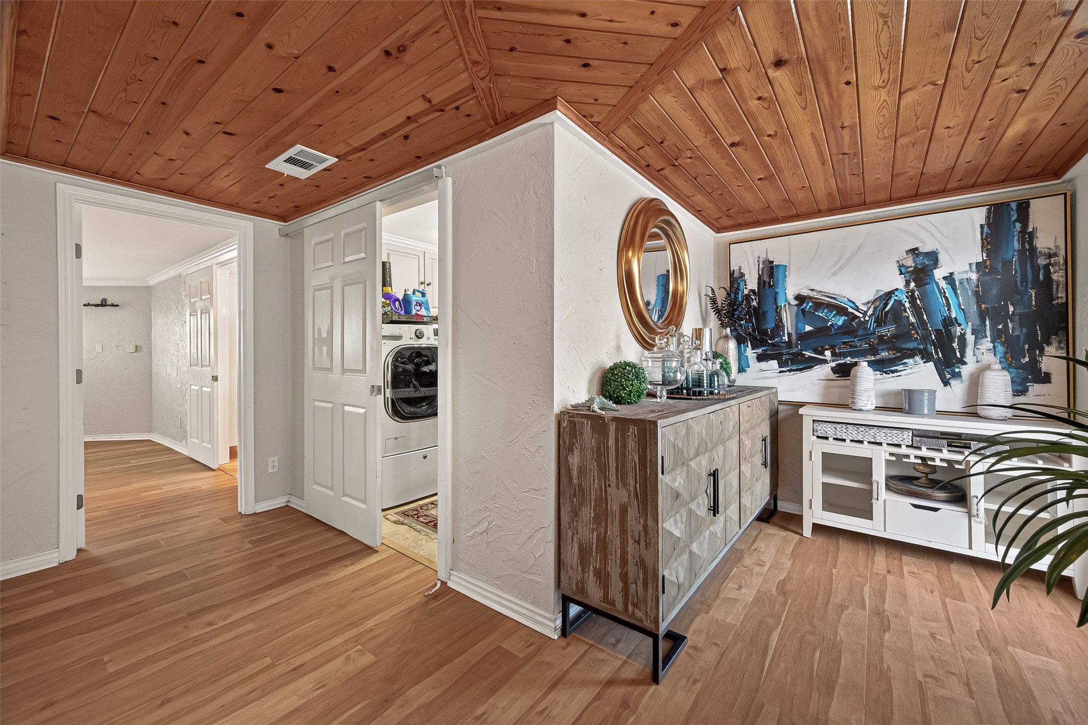 The interior showcases brilliant natural light, crisp white wall tones, striking wood-planked ceilings, and cohesive wood-tone flooring.