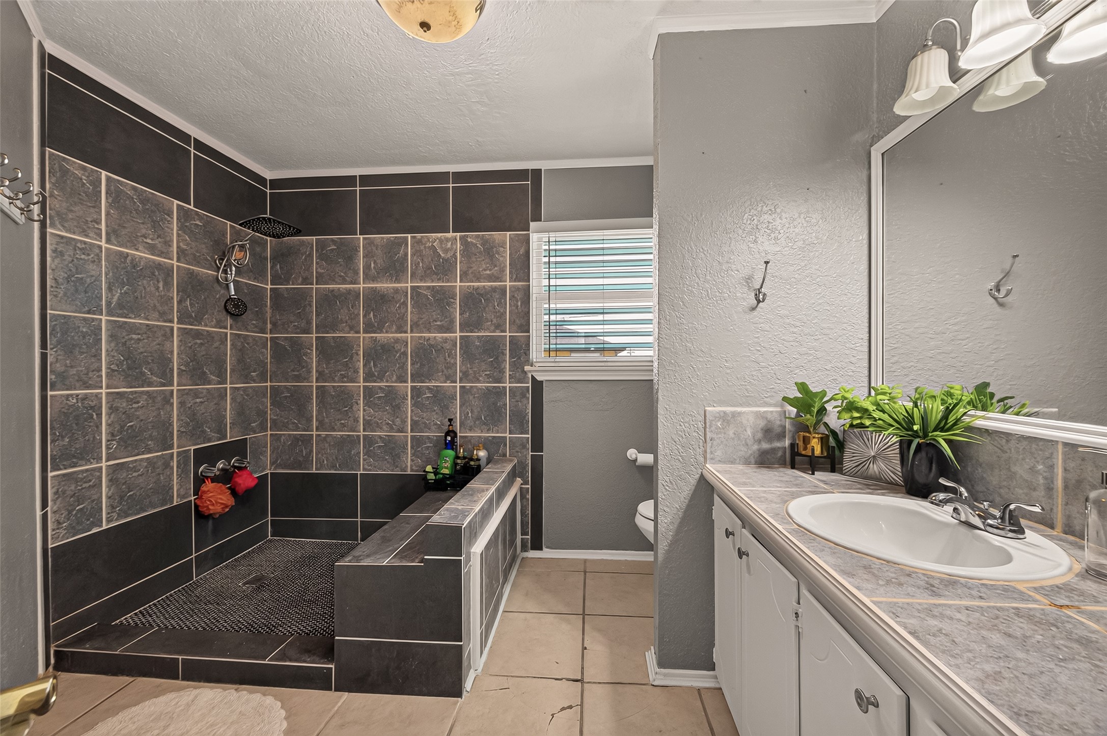 An impressive, open-concept shower hall clad in custom tile work and finished with an integrated seating bench.