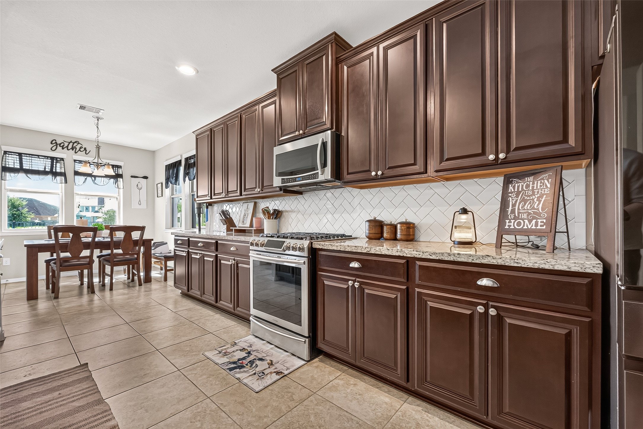 Dark cabinetry, a gas range, and a patterned tile backsplash highlight the kitchen.