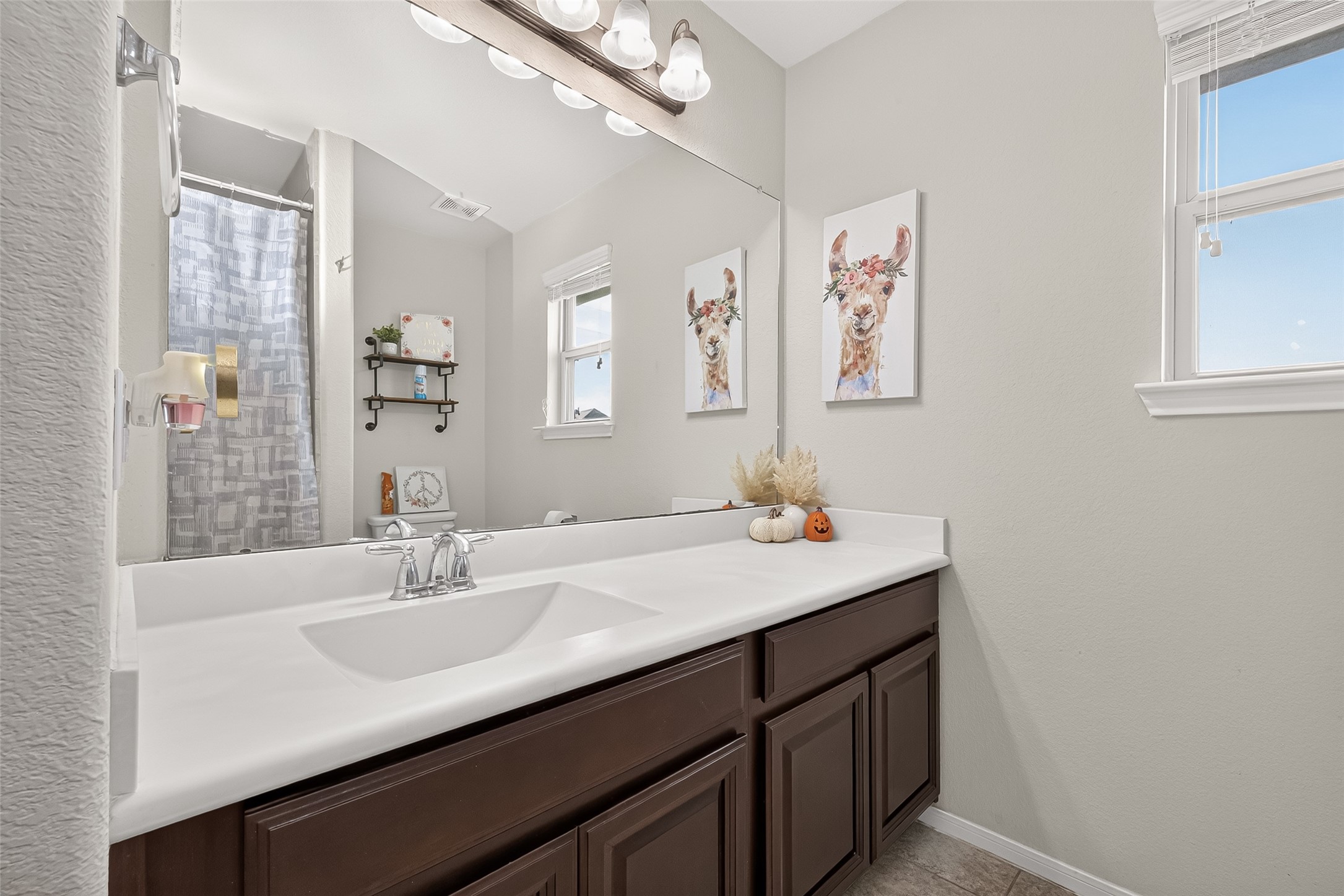 An upstairs bathroom features a wide vanity, dark cabinetry, and a window.