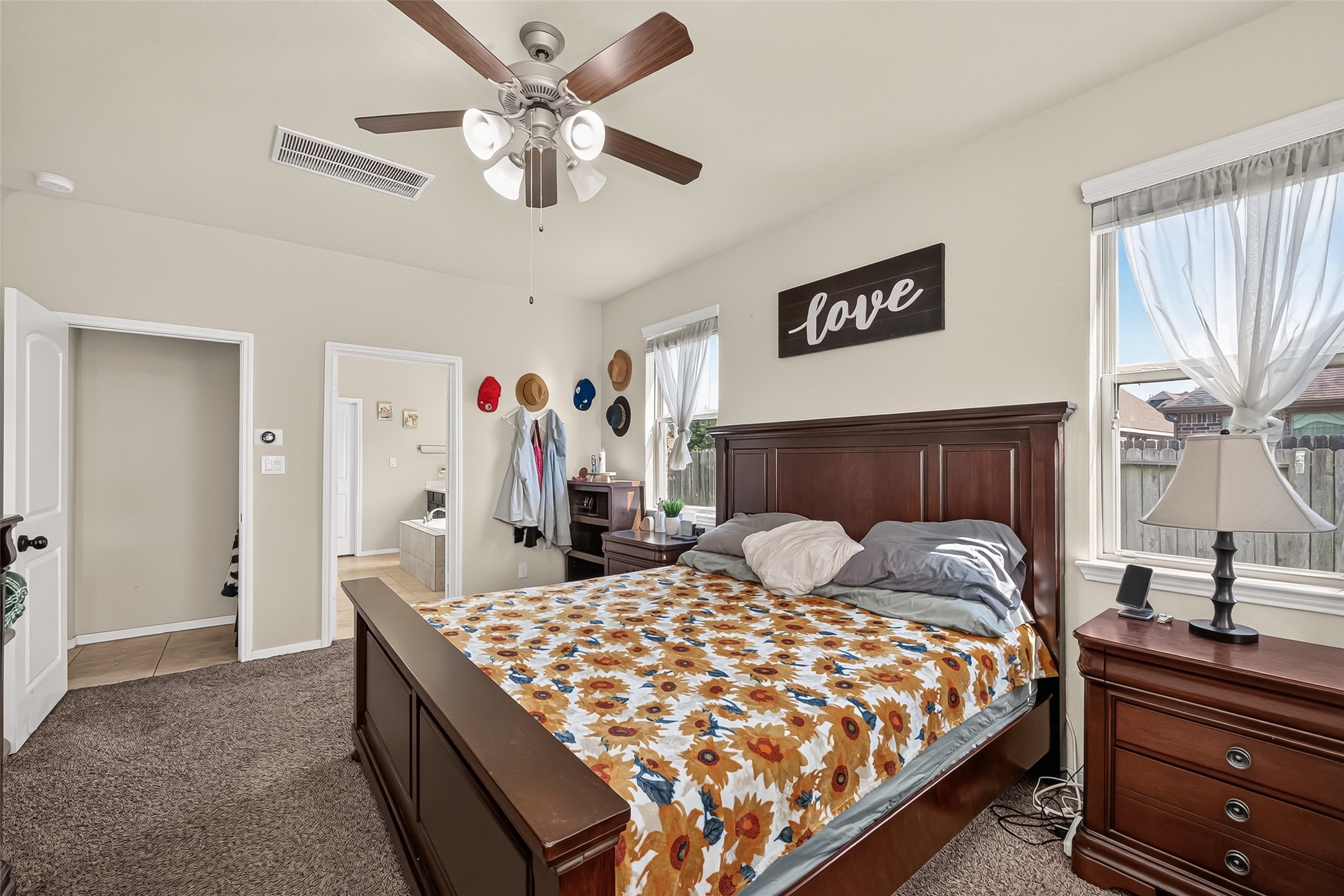 Another view of the primary retreat, featuring carpet flooring and a ceiling fan.