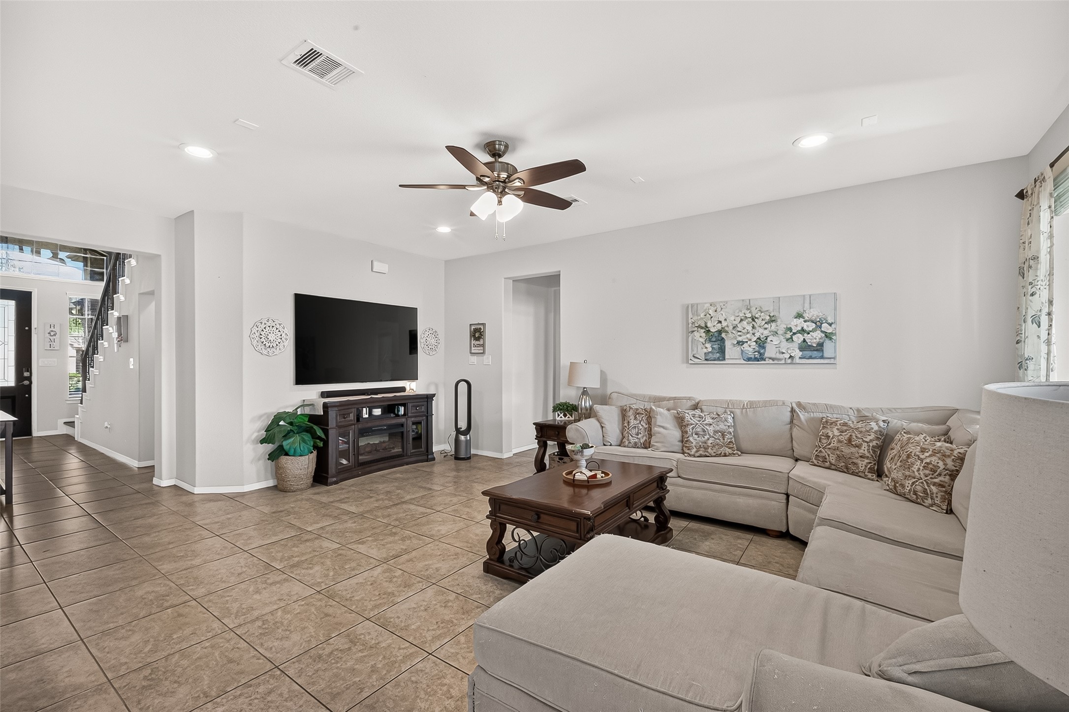 The spacious living room offers tile flooring, a ceiling fan, and room to relax.