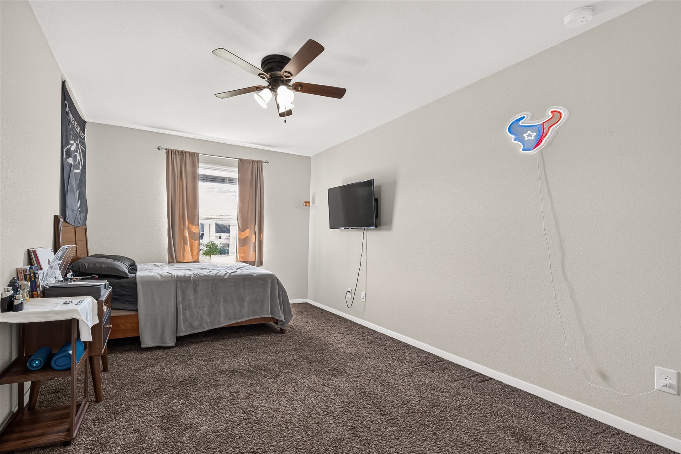 An upstairs bedroom offers carpet flooring, natural light, and a ceiling fan.