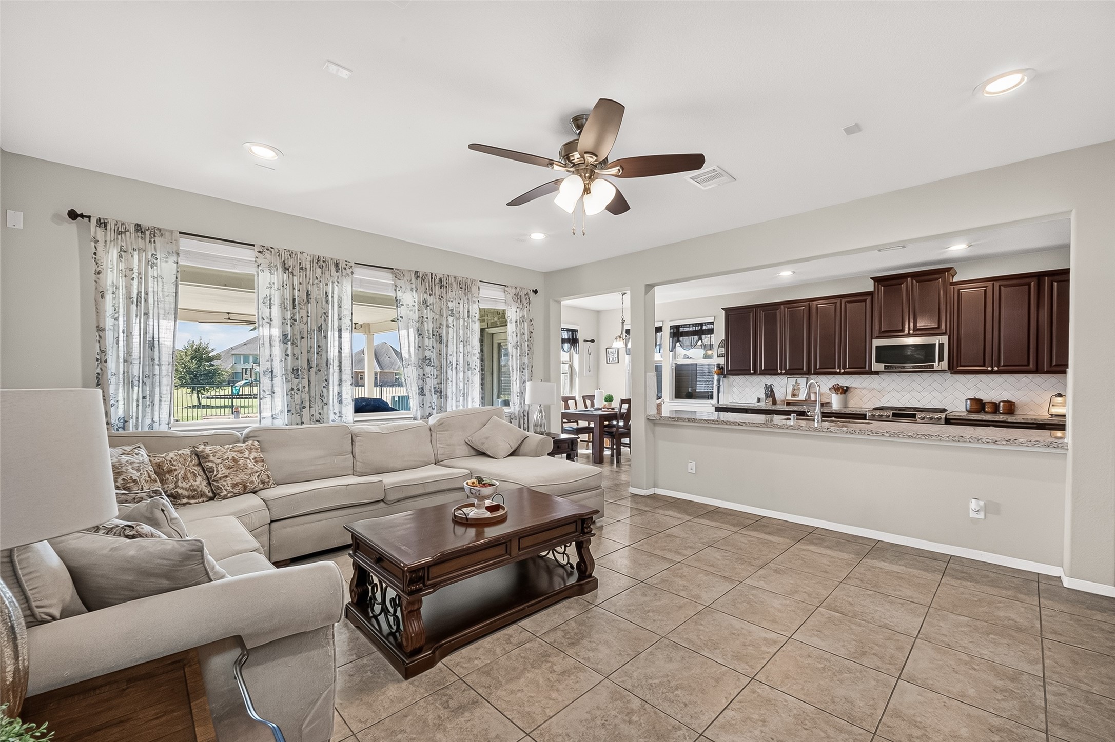 An open living area connects the kitchen and breakfast bar, with windows overlooking the backyard.