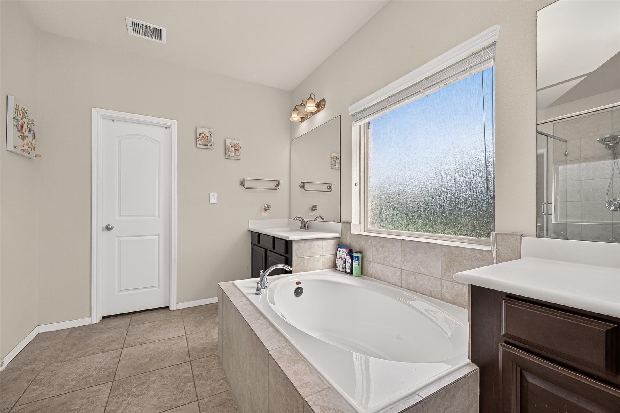 Natural light, tile flooring, and dark cabinetry complete the primary bathroom.