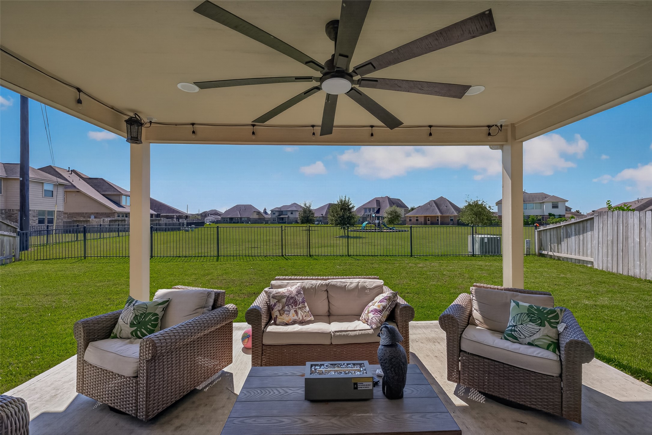 Relax beneath the covered patio with a ceiling fan and open views toward the park.