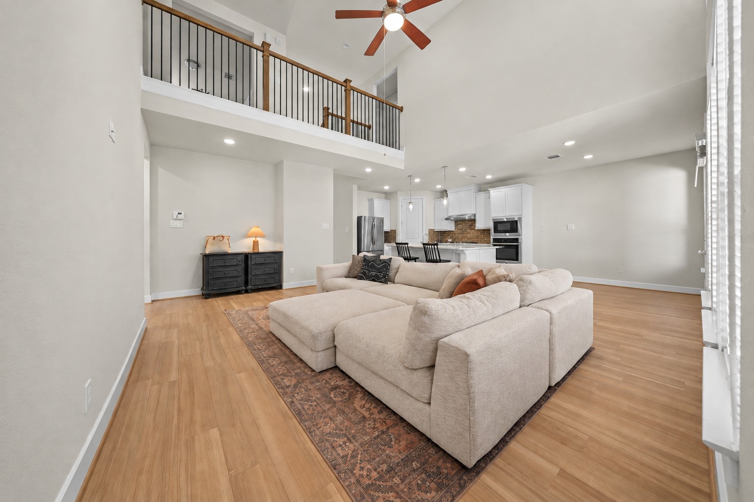 Soaring ceilings and wood-look flooring give this living room an open, airy feel, with an easy view into the kitchen for everyday living and entertaining. Soaring ceilings and wood-look flooring give this living room an open, airy feel, with an easy view into the kitchen for everyday living and entertaining.