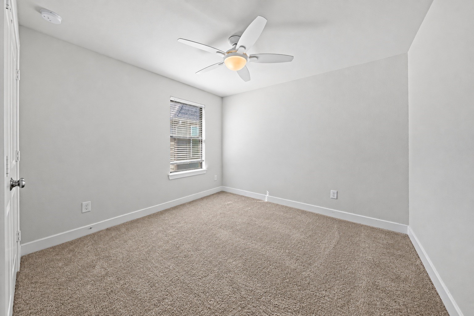 Another upstairs bedroom with soft carpet, a ceiling fan and a window that brings in natural light, ready for guests, family, or a hobby space.