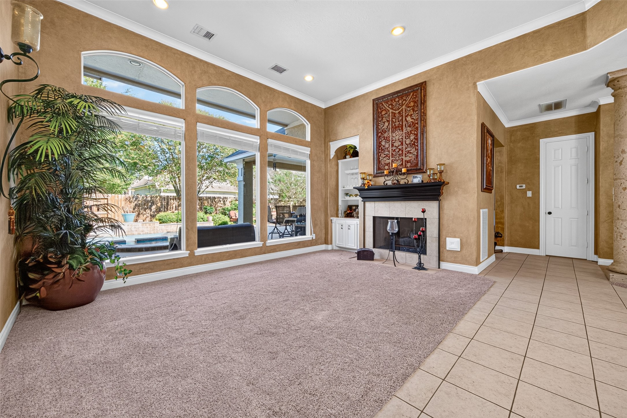 Formal living room features a wall of picture windows looking out to the pool and hot tub, a fire place and