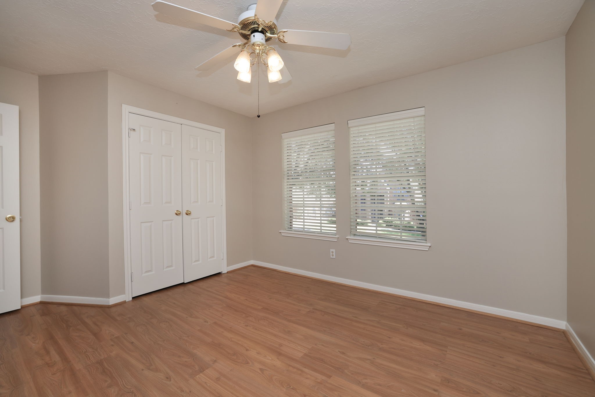Spacious second upstairs bedroom with double closets and peaceful front yard views.