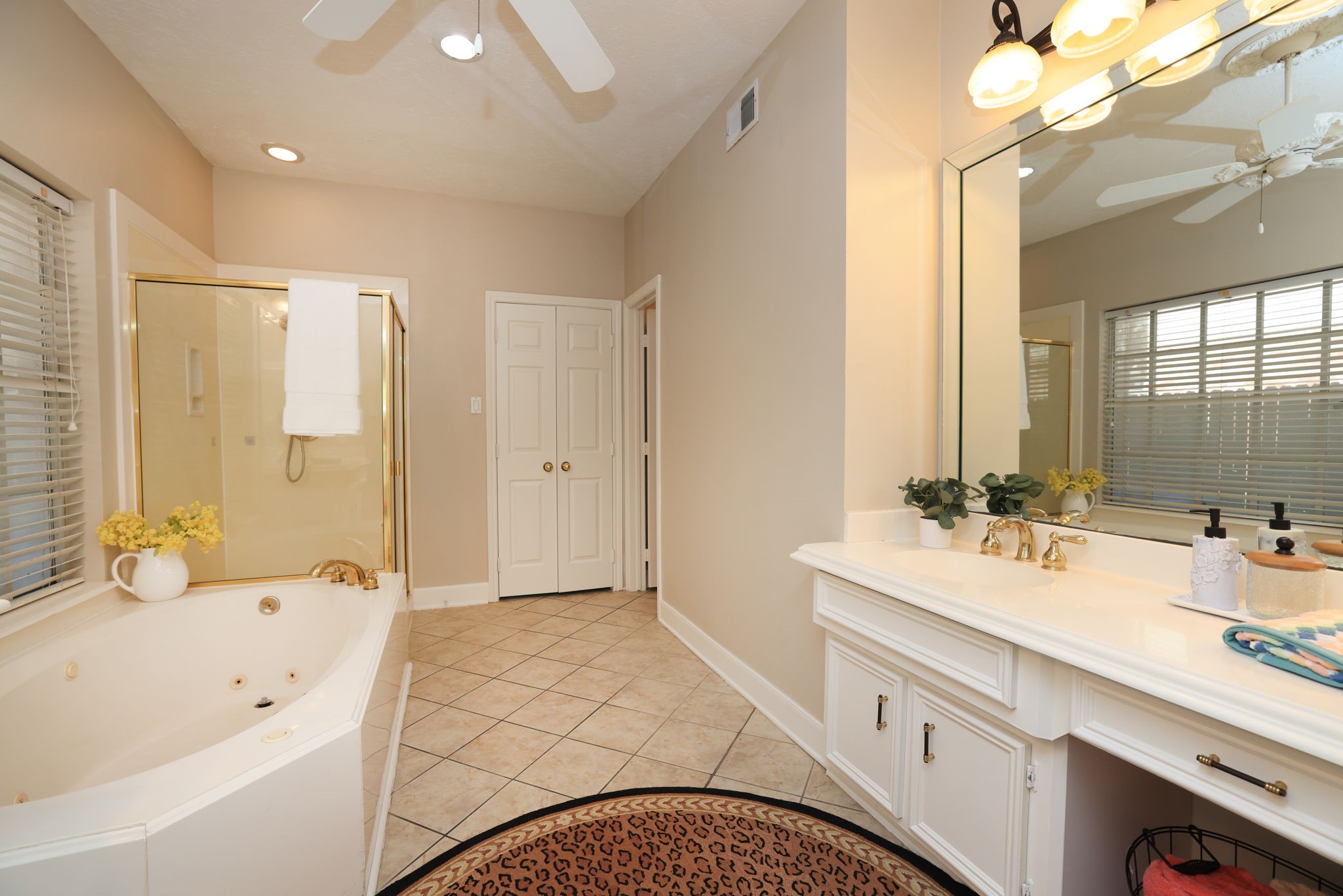 Primary bath features a jetted soaking tub, separate shower, and dual vanities with gold-tone fixtures.