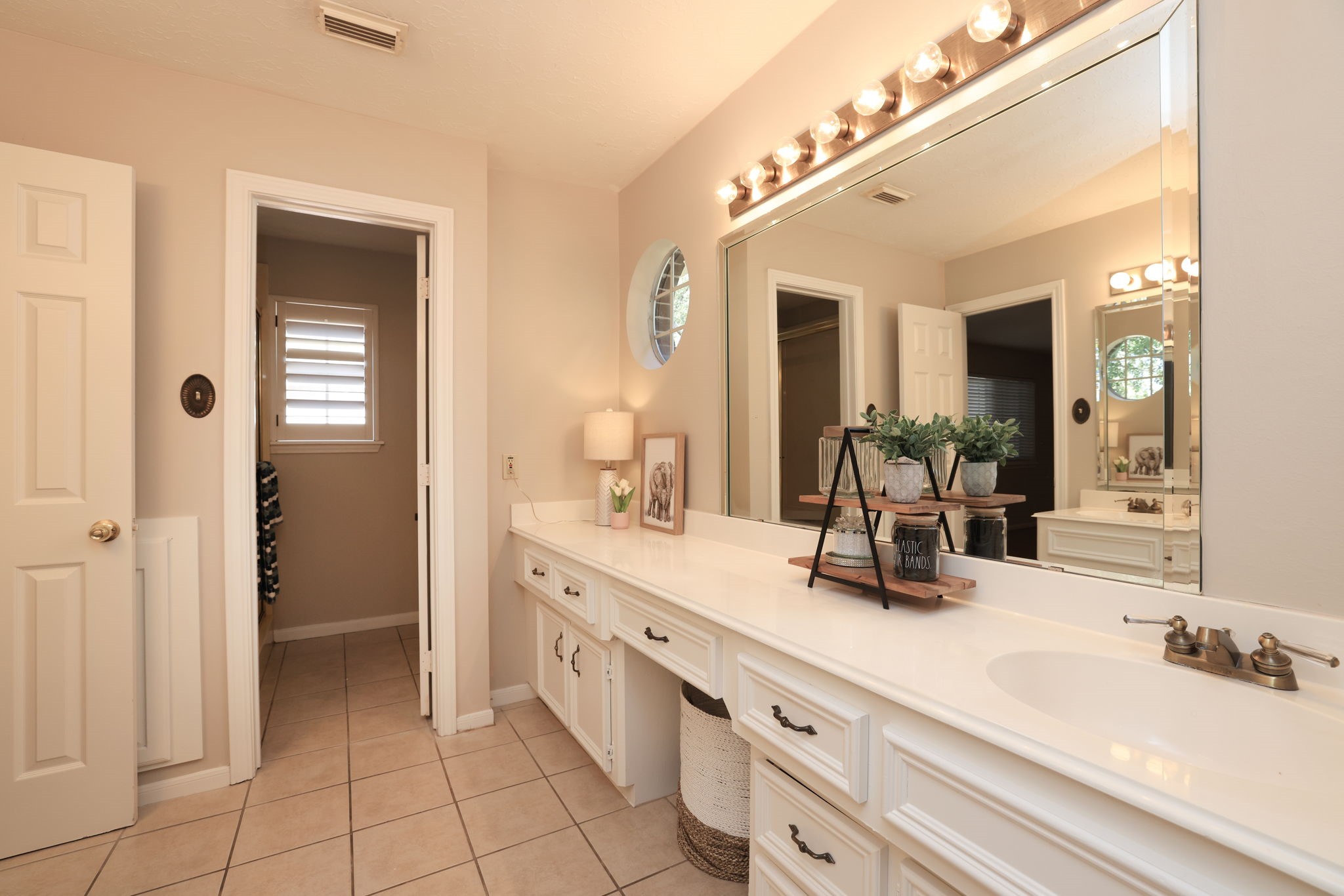 Full upstairs bath with extended dual vanities, updated lighting, and neutral finishes.