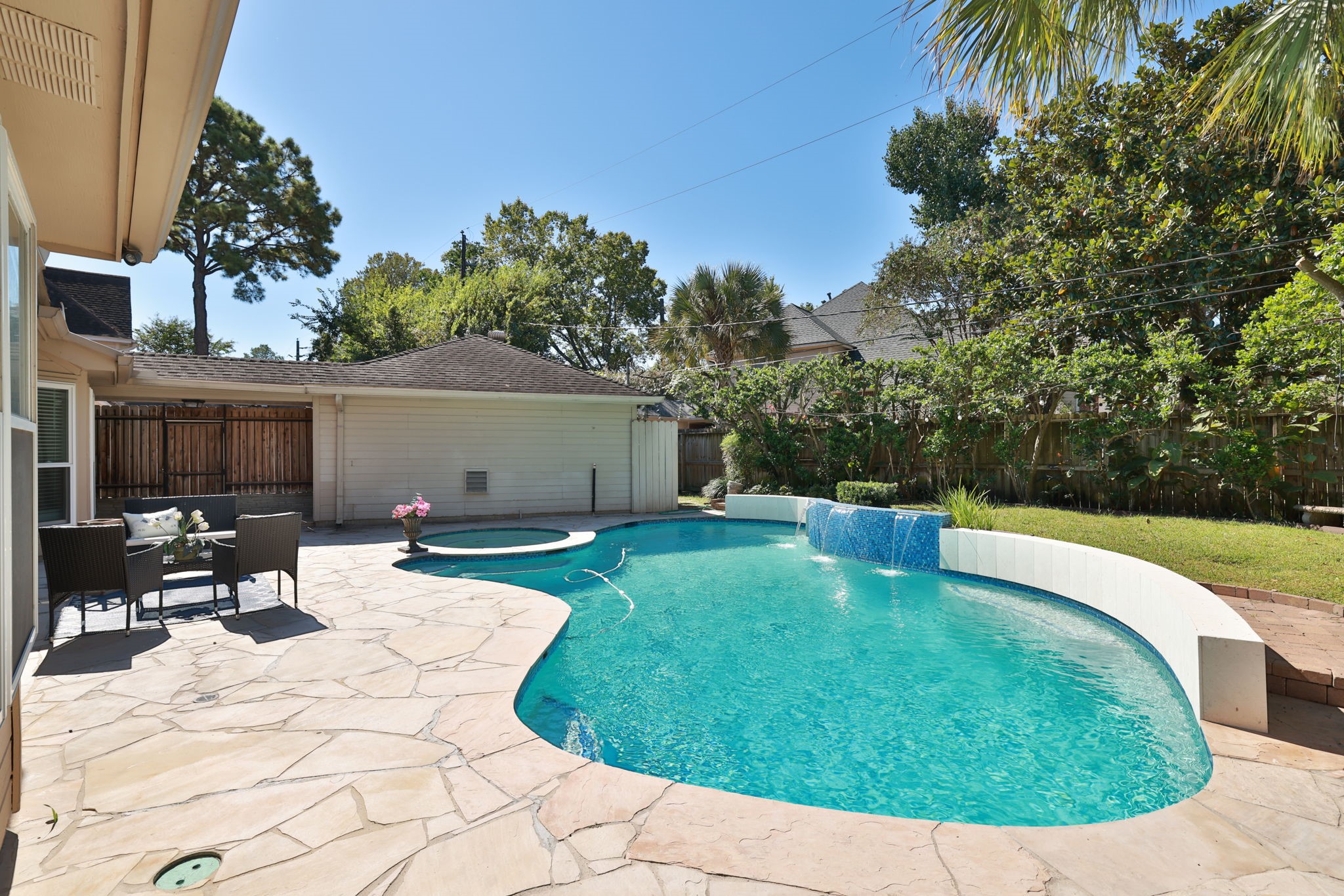 Expansive stone patio provides ample seating and entertaining space beside the pool.
