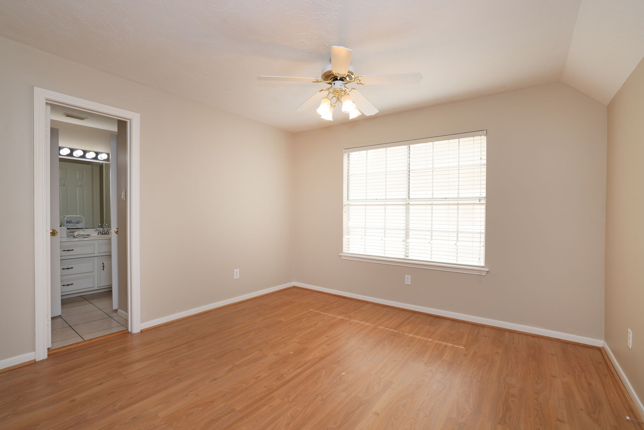 Generously sized secondary bedroom with large window, ceiling fan, and walk-in closet.