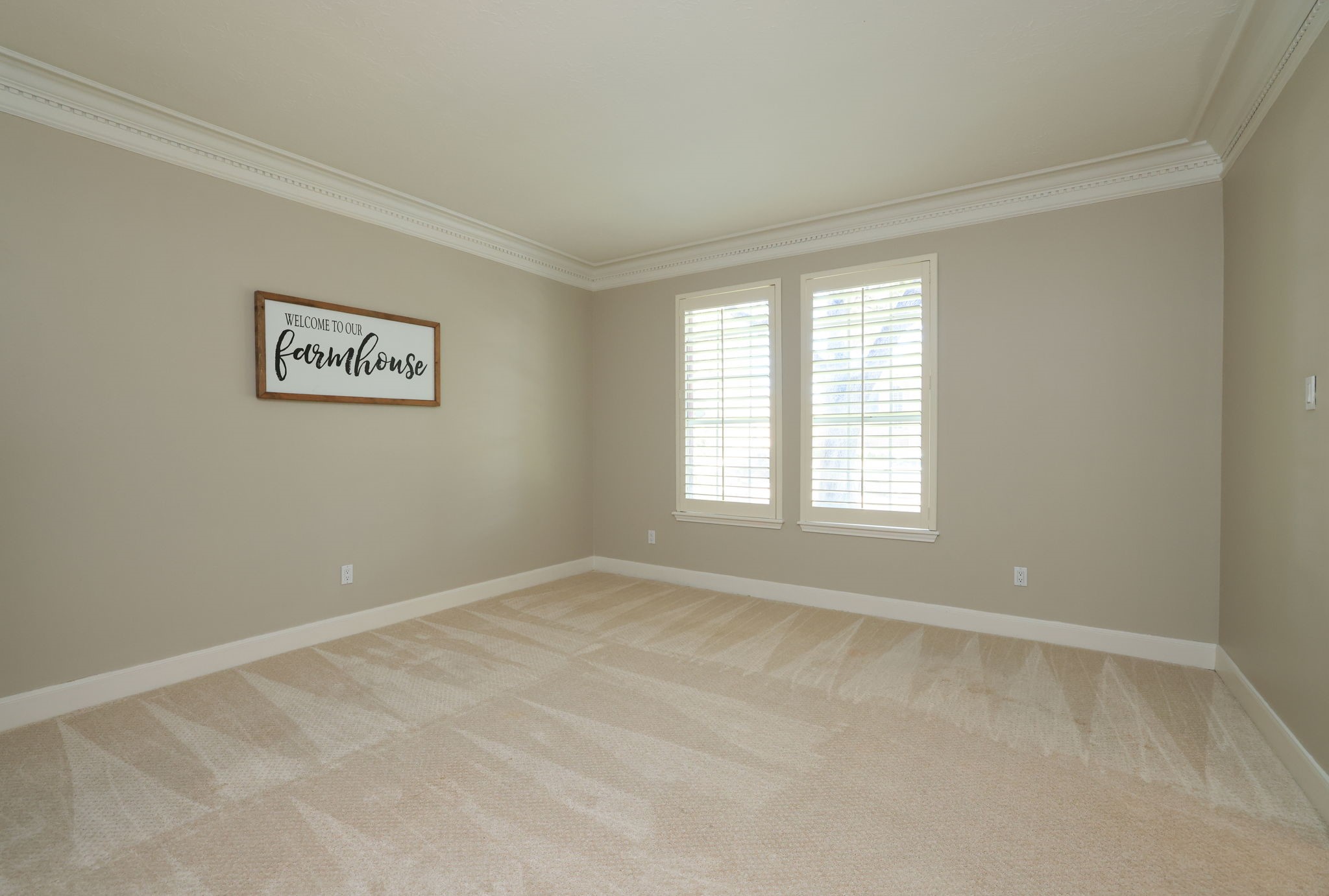 Flexible formal living room ideal for formal living or home office with crown molding, neutral palette, and plantation shutters.