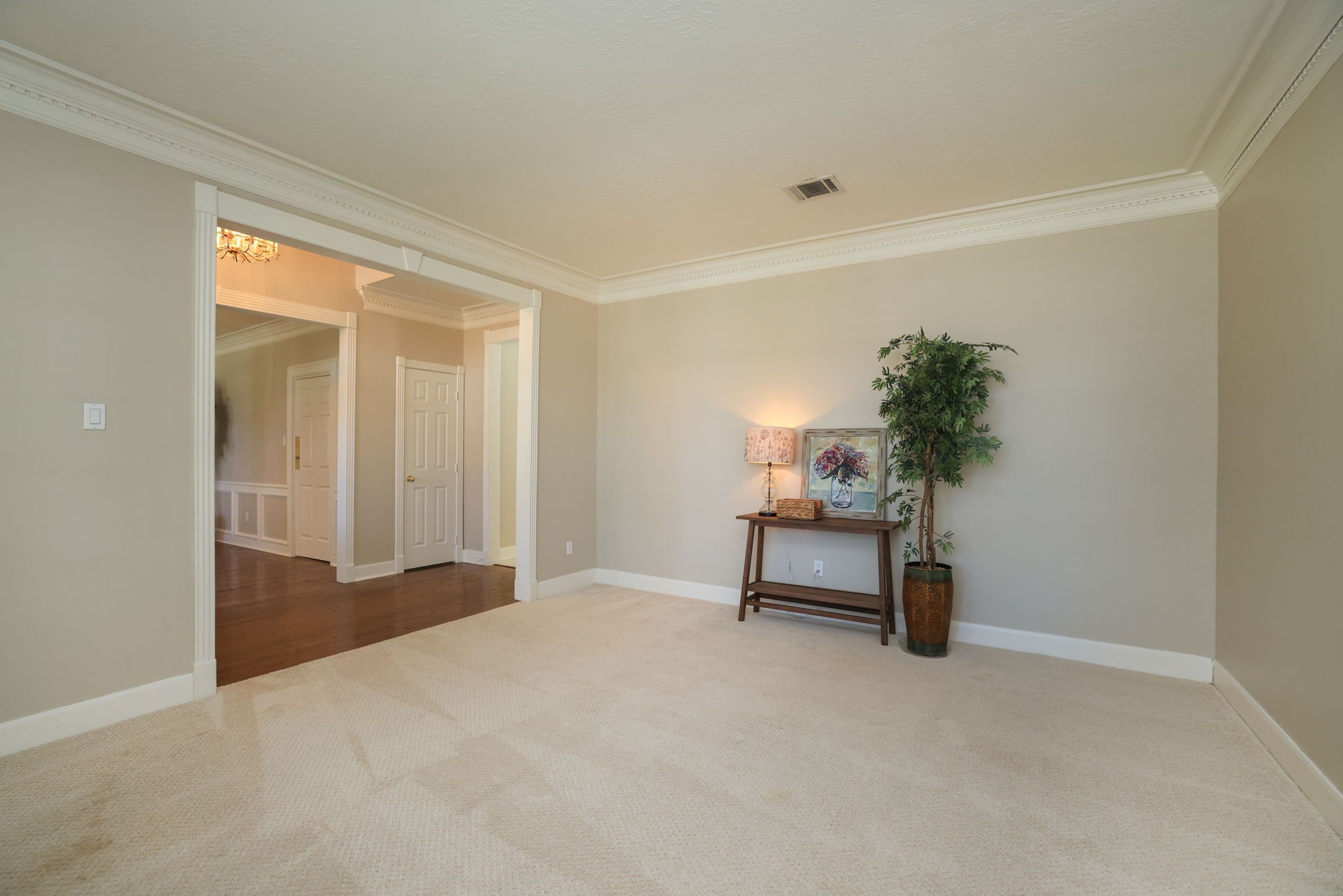 Spacious formal living area or study with soft neutral tones, crown molding, and views toward the grand foyer.