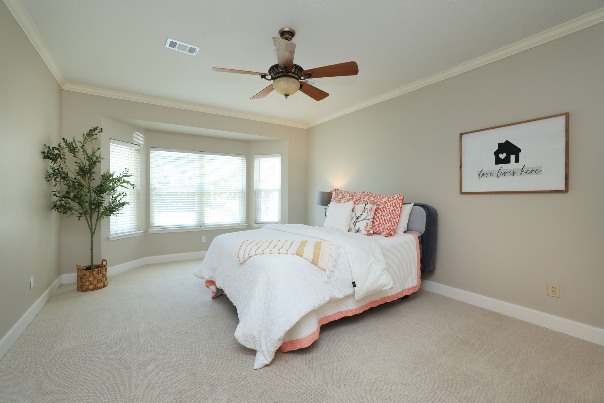 Serene primary retreat with bay window seating area, crown molding, and peaceful backyard views.