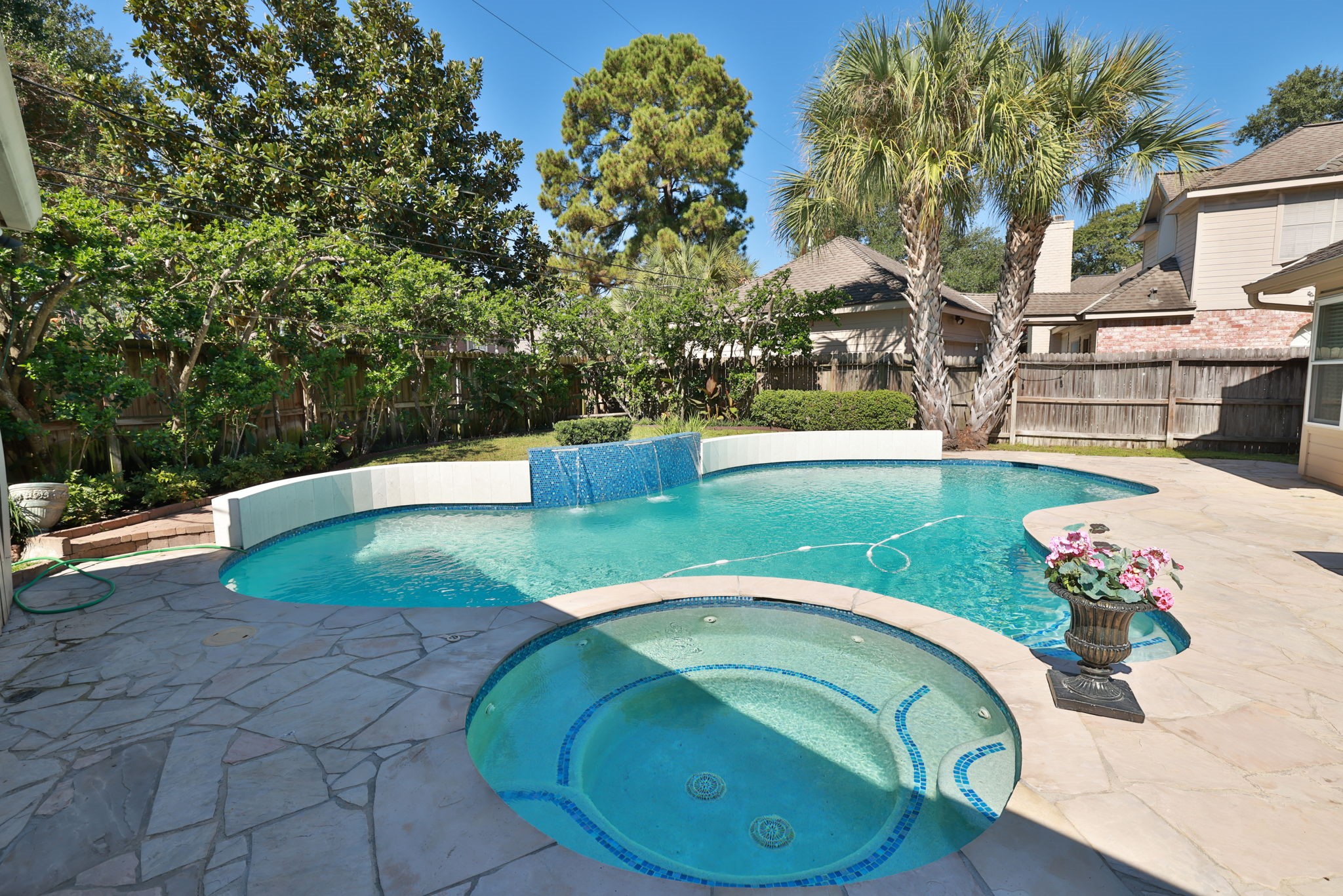 Cascading water feature flows gently over sparkling blue tiled raised deck  ideal for relaxing or entertaining.