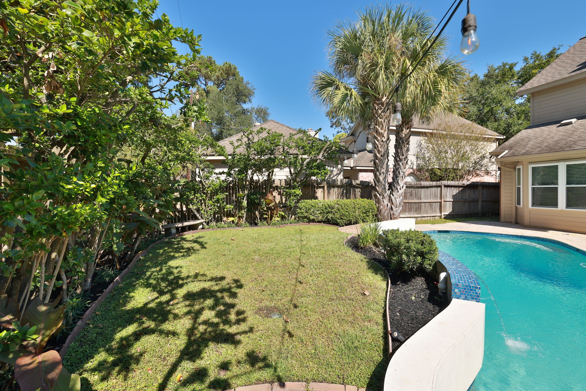 Manicured lawn and mature trees offer both sun and shade, creating a peaceful outdoor retreat.