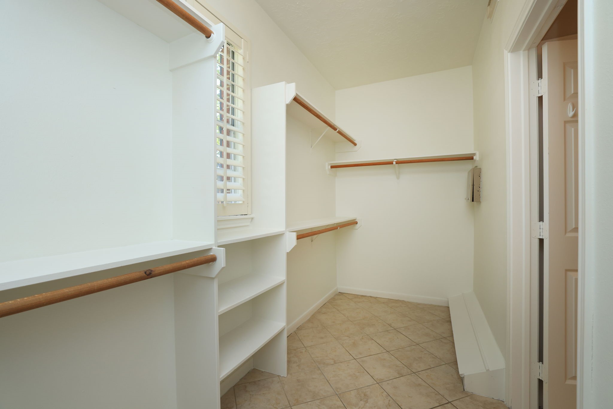 Spacious walk-in closet with custom built-ins, abundant hanging space, shelving, and a window for natural light.