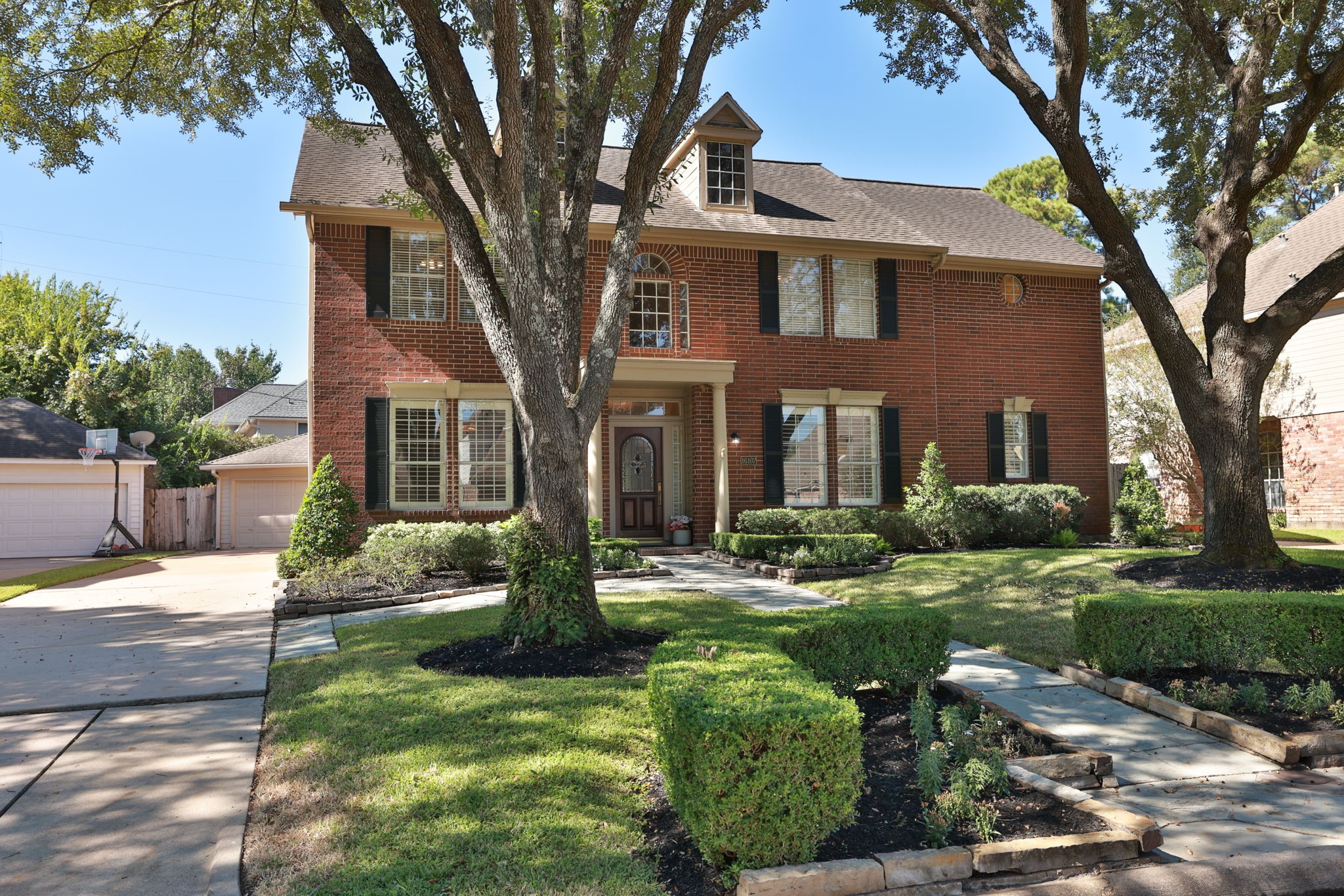 Impressive exterior with extended driveway leading to a detached two-car garage and gated side yard access.