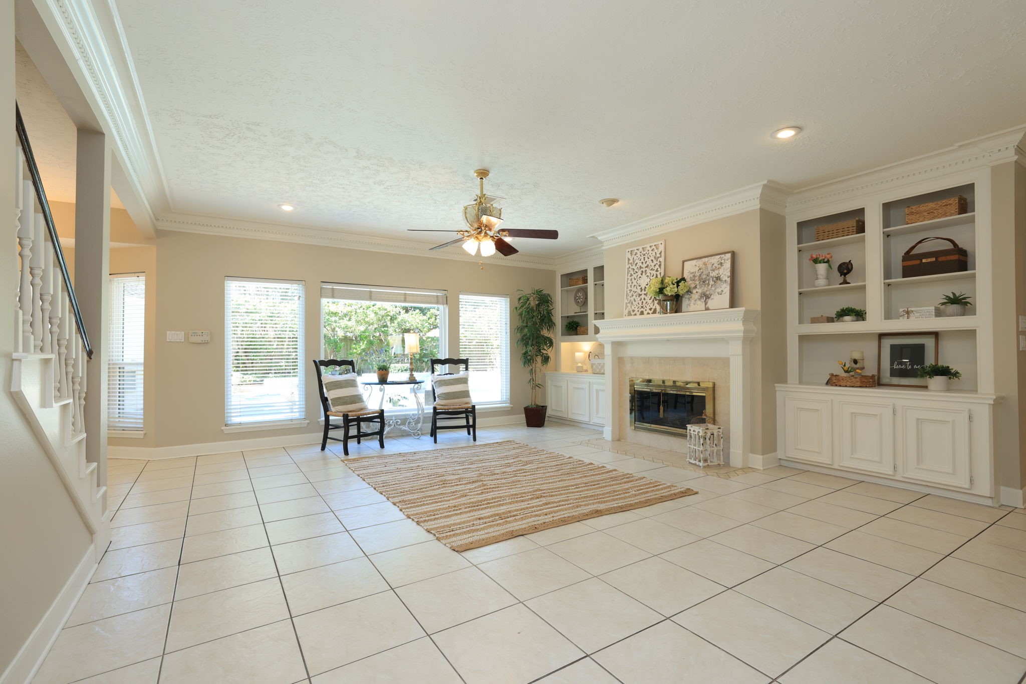 Bright and inviting family room with custom built-ins, crown molding, and a gas fireplace as the centerpiece.
