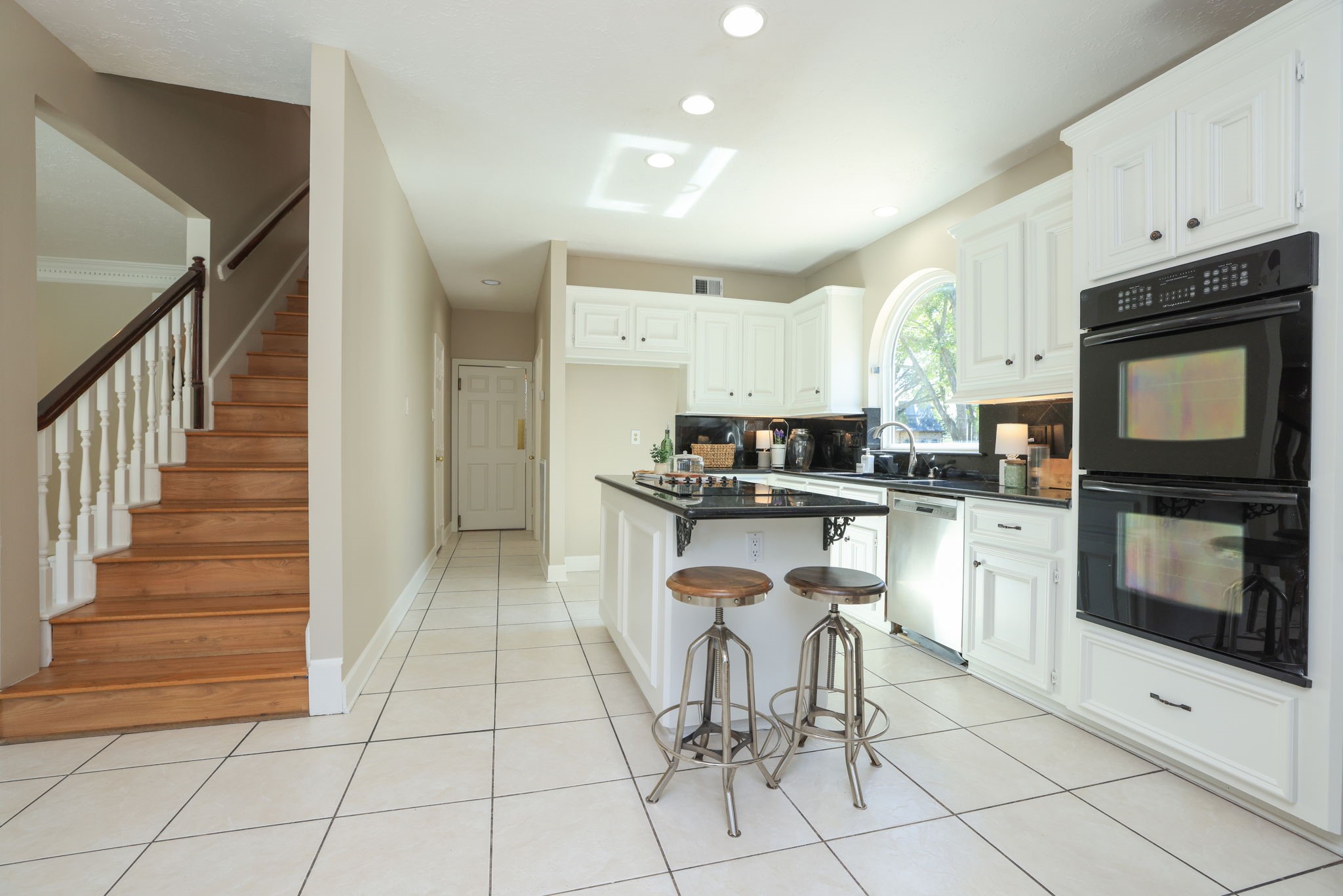 Light-filled kitchen with large island, stainless appliances, and seamless access to the upstairs and utility areas.