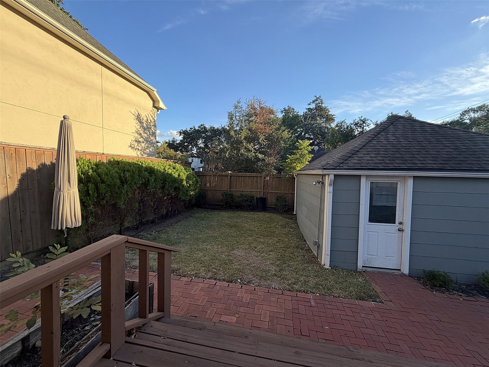 Backyard Overview: Fenced backyard with green lawn, mature trees, and outdoor entertaining space.