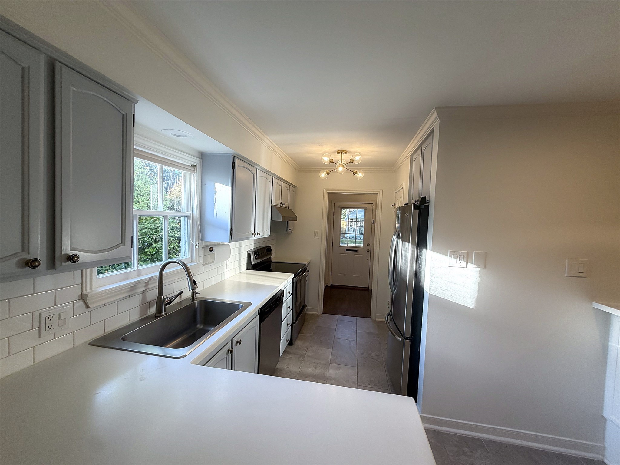 Kitchen Overview: Bright kitchen featuring white cabinetry, modern appliances, and a convenient breakfast bar.