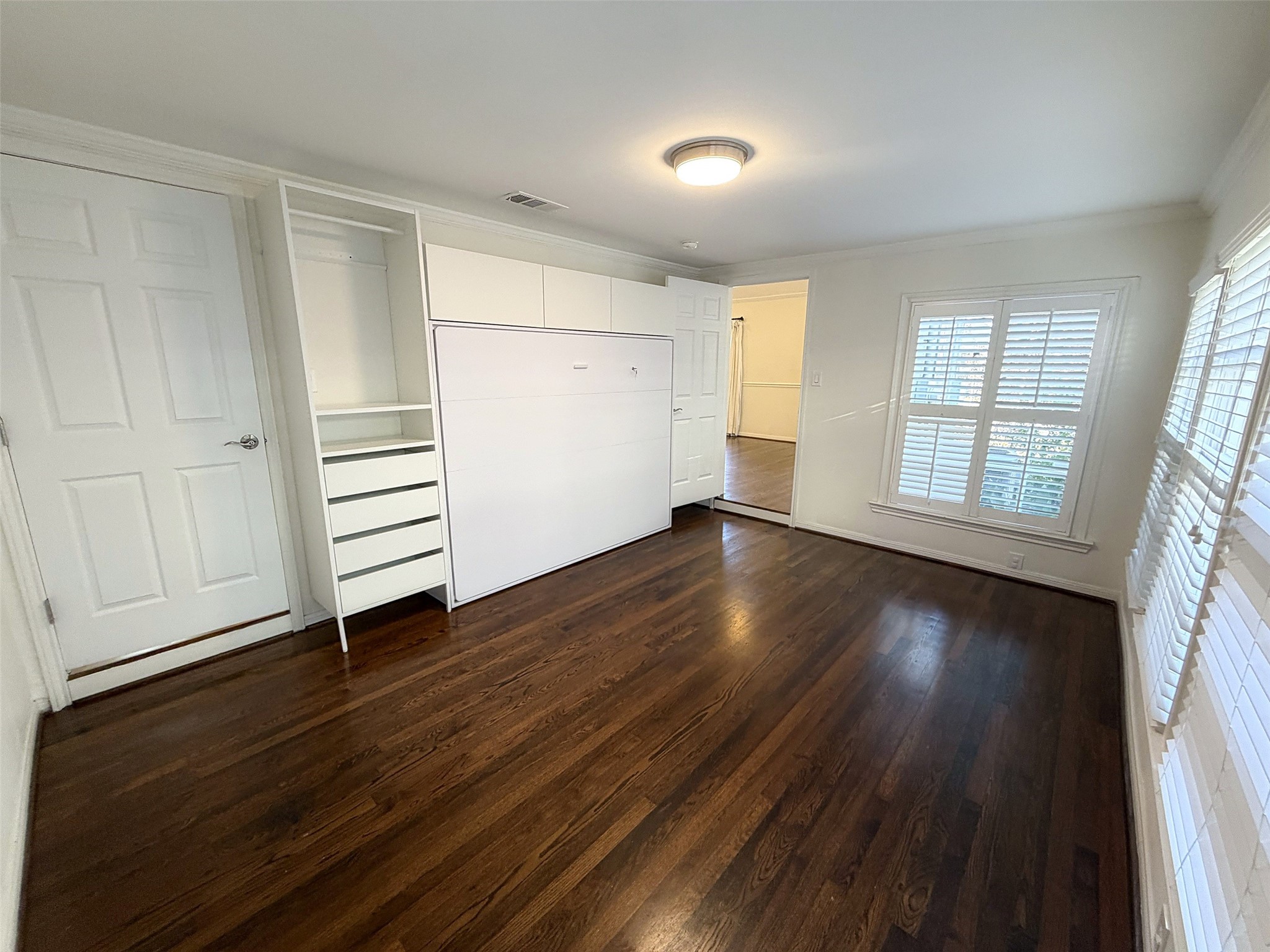 Bedroom/Study: Flexible room featuring a desk, comfortable seating, and natural light, ideal for a home office.  There is a built-in Murphy bed with integrated drawers and shelving for the weekend visitor.