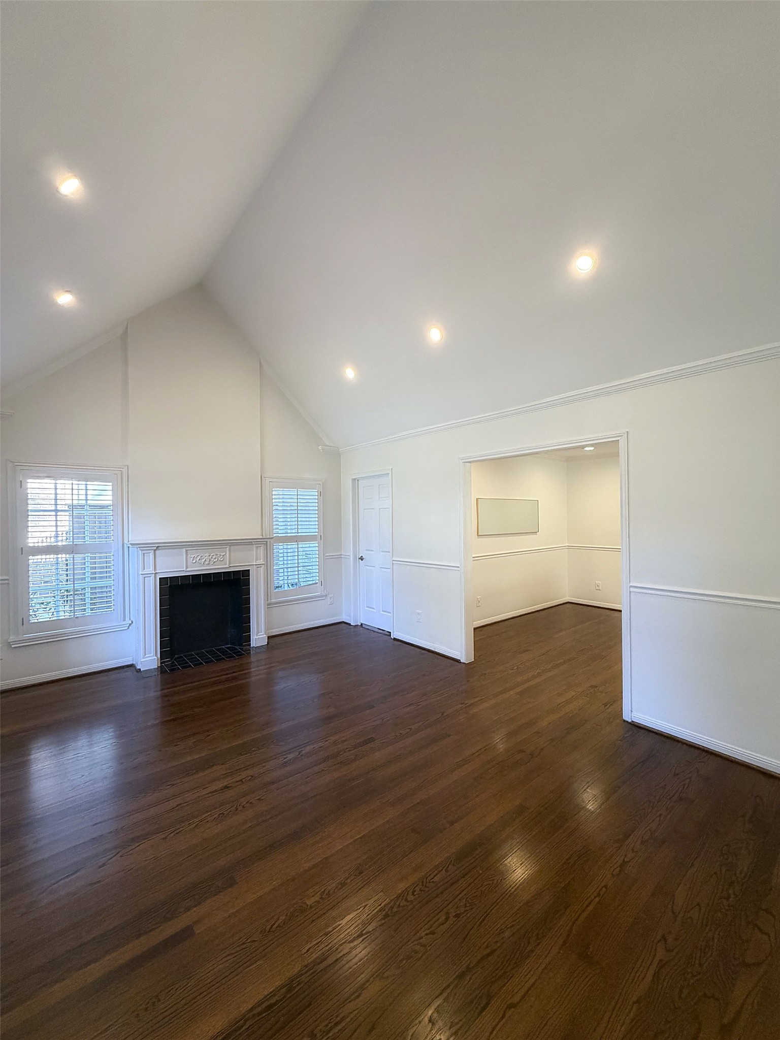 Bright living area with high ceilings, hardwood floors, and large windows.