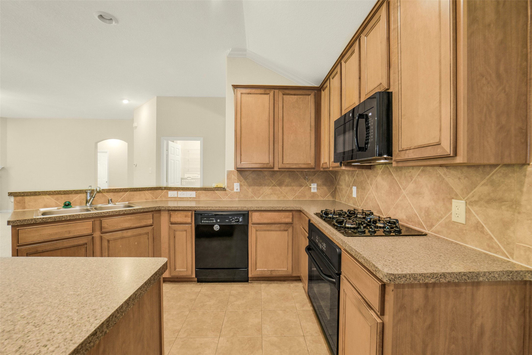 Spacious kitchen with warm wood cabinetry, sleek countertops, and modern appliances, offering both functionality and style for culinary enthusiasts.