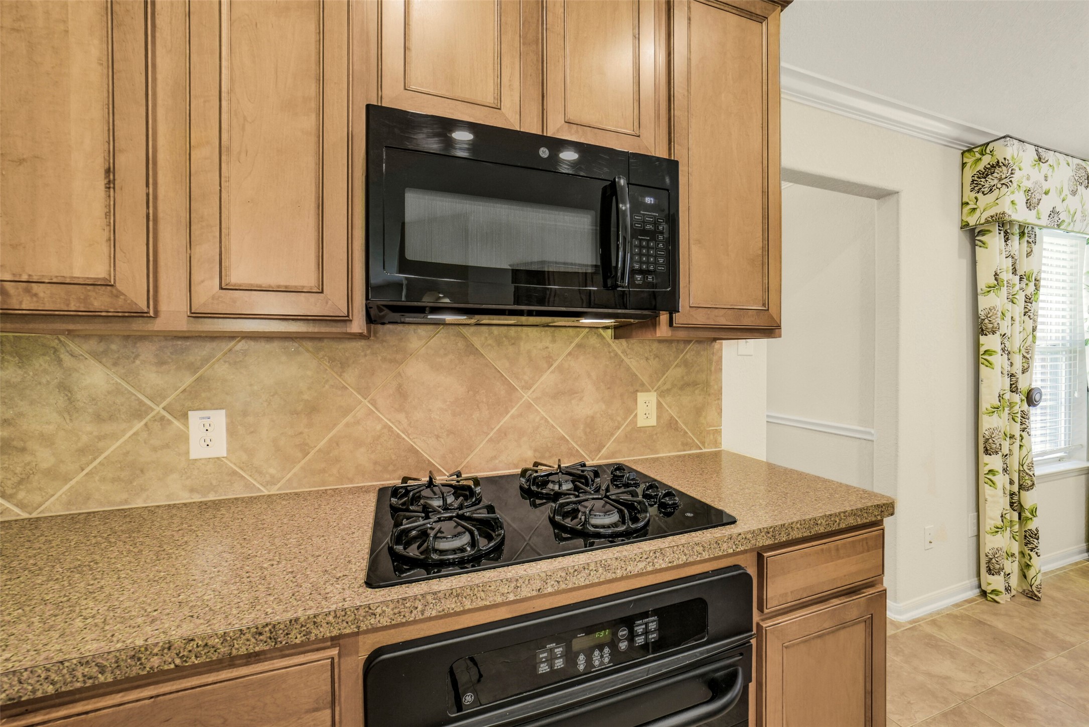 Modern kitchen with sleek black appliances, warm wooden cabinetry, and a stylish tile backsplash.