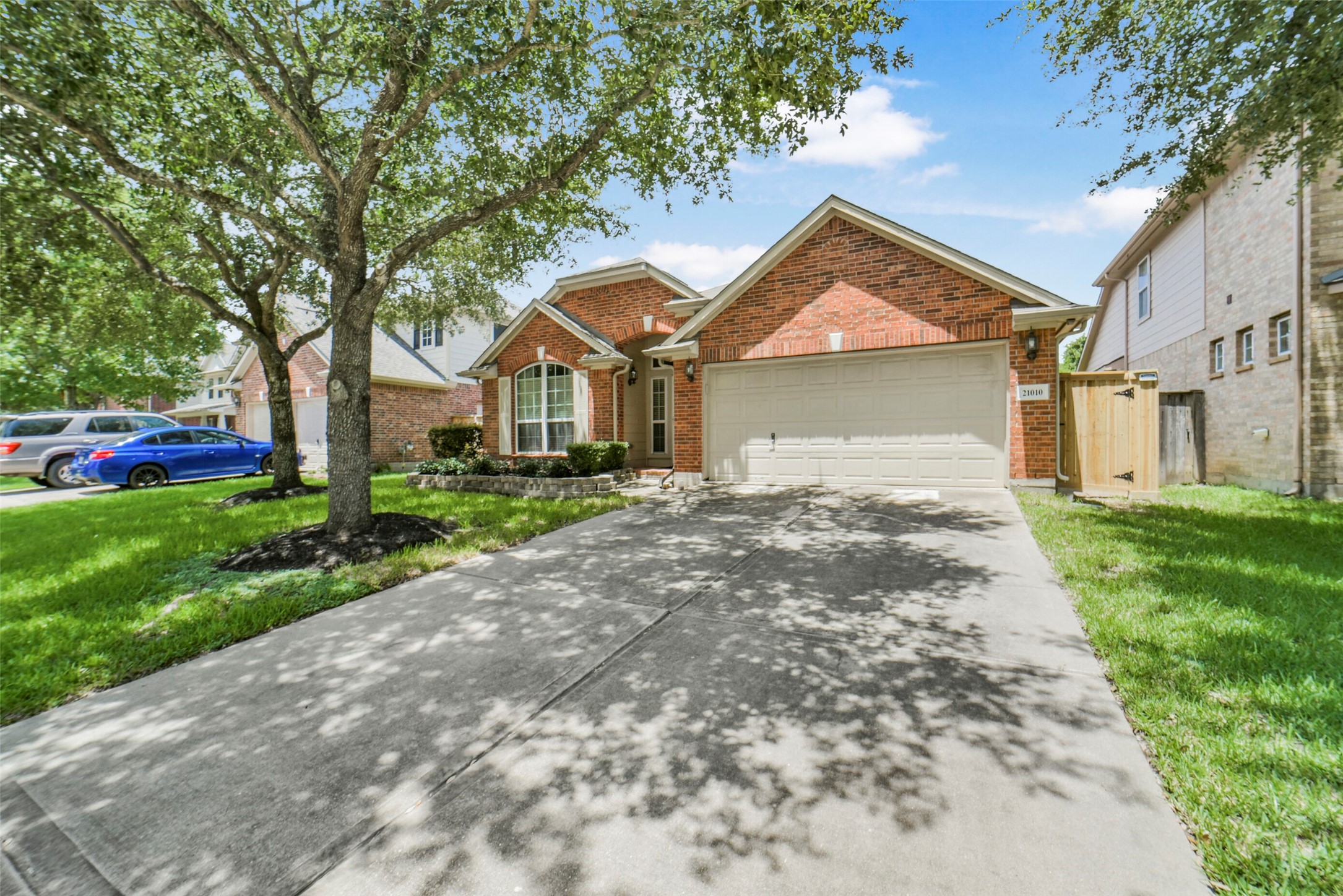 Charming brick home with a well-maintained lawn, mature trees, and a spacious driveway leading to a two-car garage.