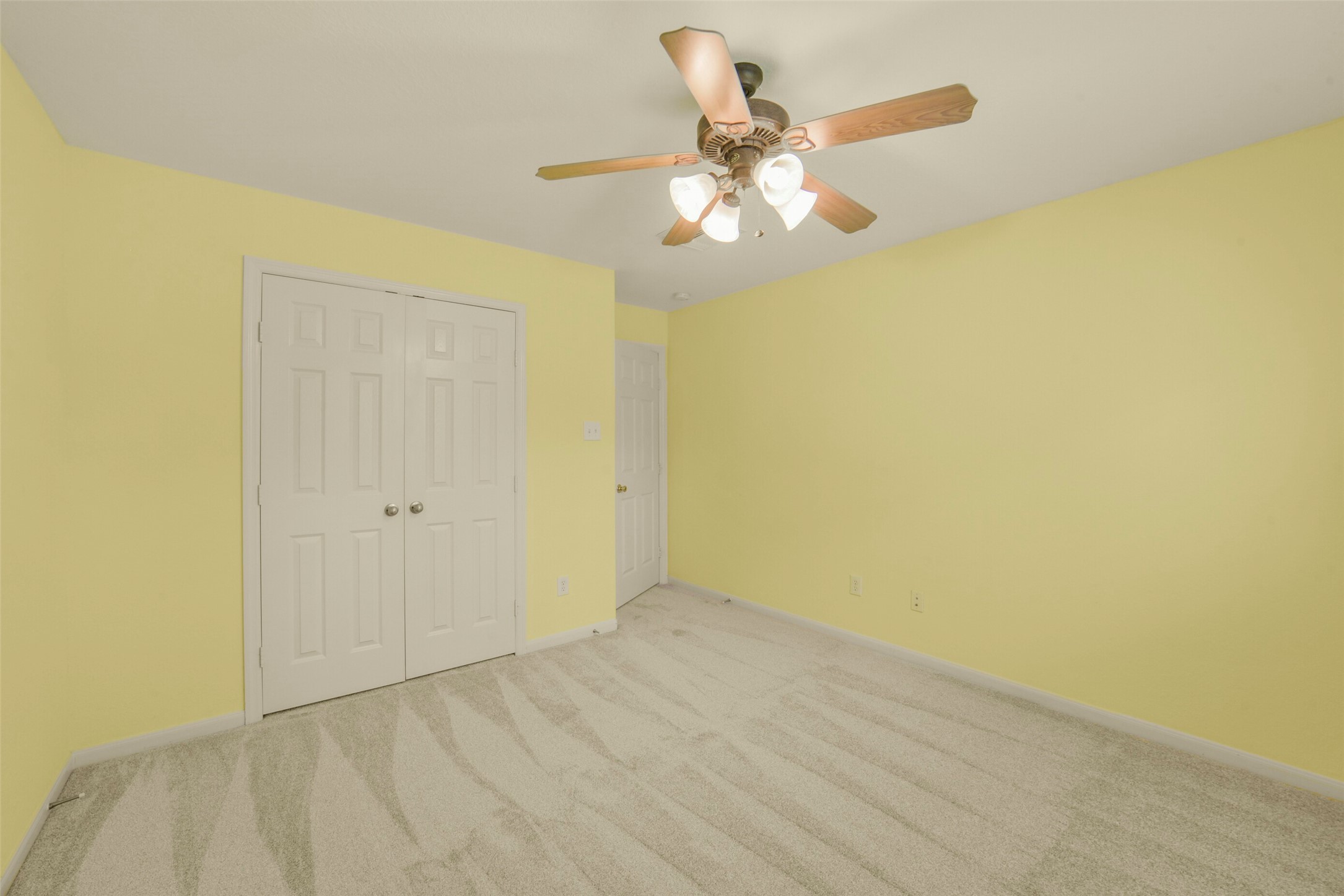 Bright and airy secondary bedroom with plush carpet, and a ceiling fan for comfort.