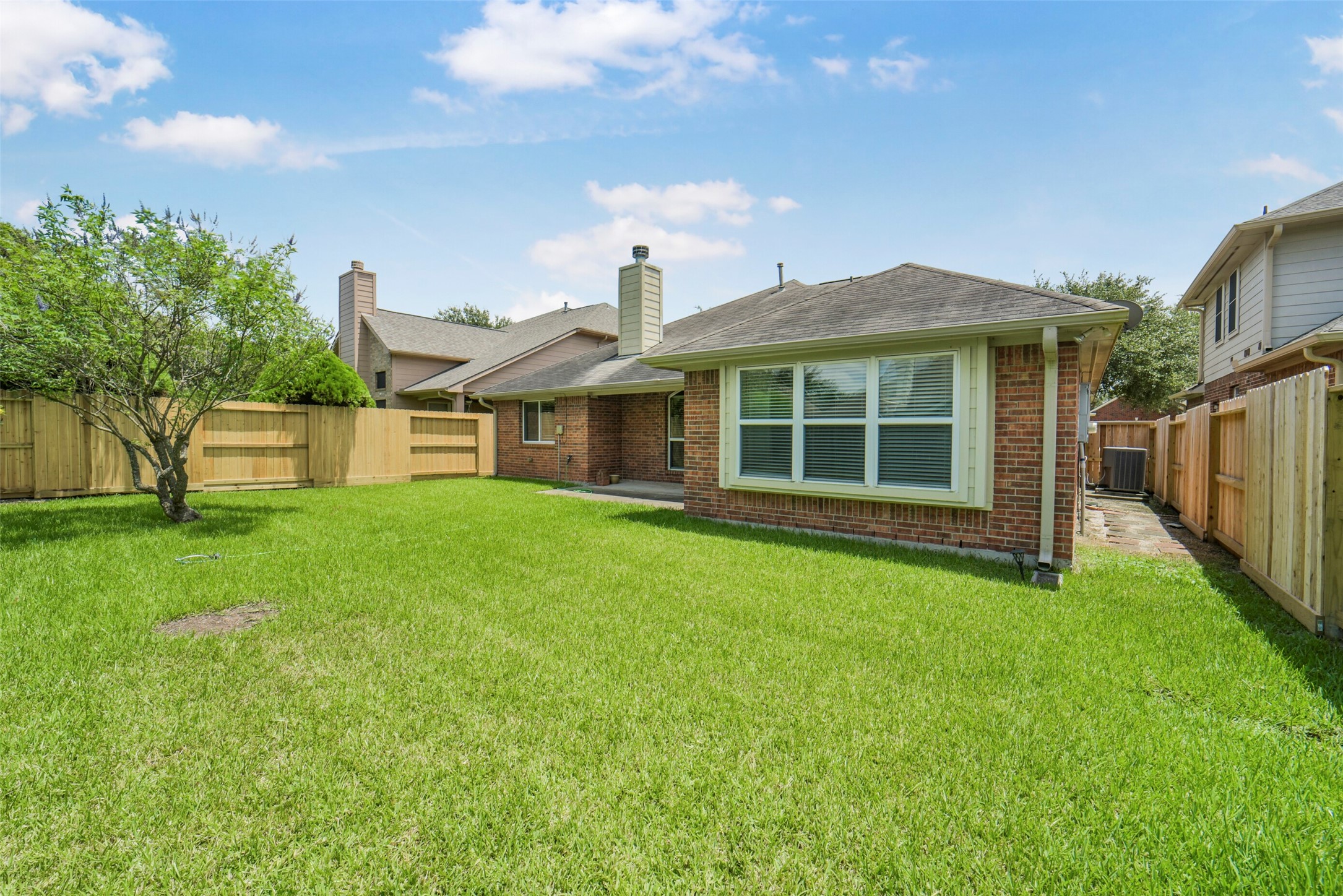 Spacious backyard with lush green lawn and a charming brick exterior, perfect for outdoor activities and relaxation.