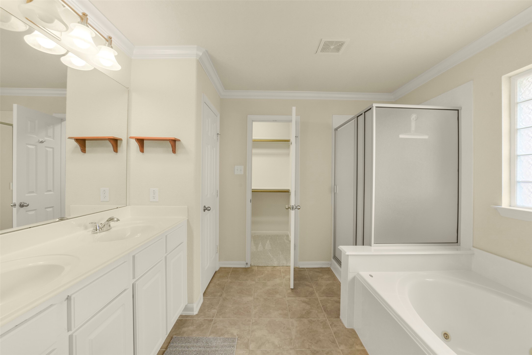 Spacious primary bathroom featuring a dual-sink vanity, large soaking tub, separate shower, and convenient walk-in closet.