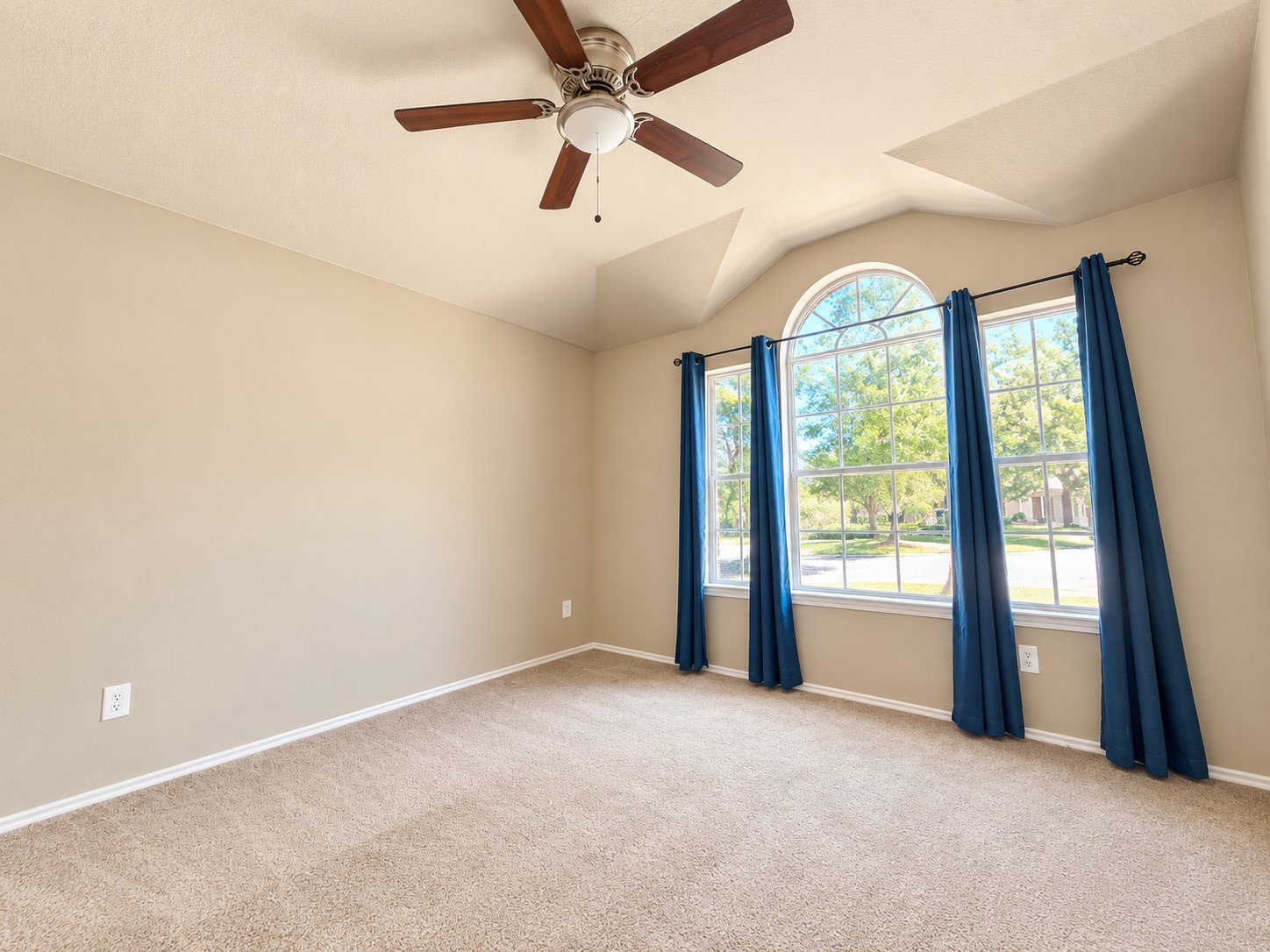 Spacious second bedroom featuring vaulted ceilings, a ceiling fan, and beautiful arched windows that fill the room with natural light. New carpet.