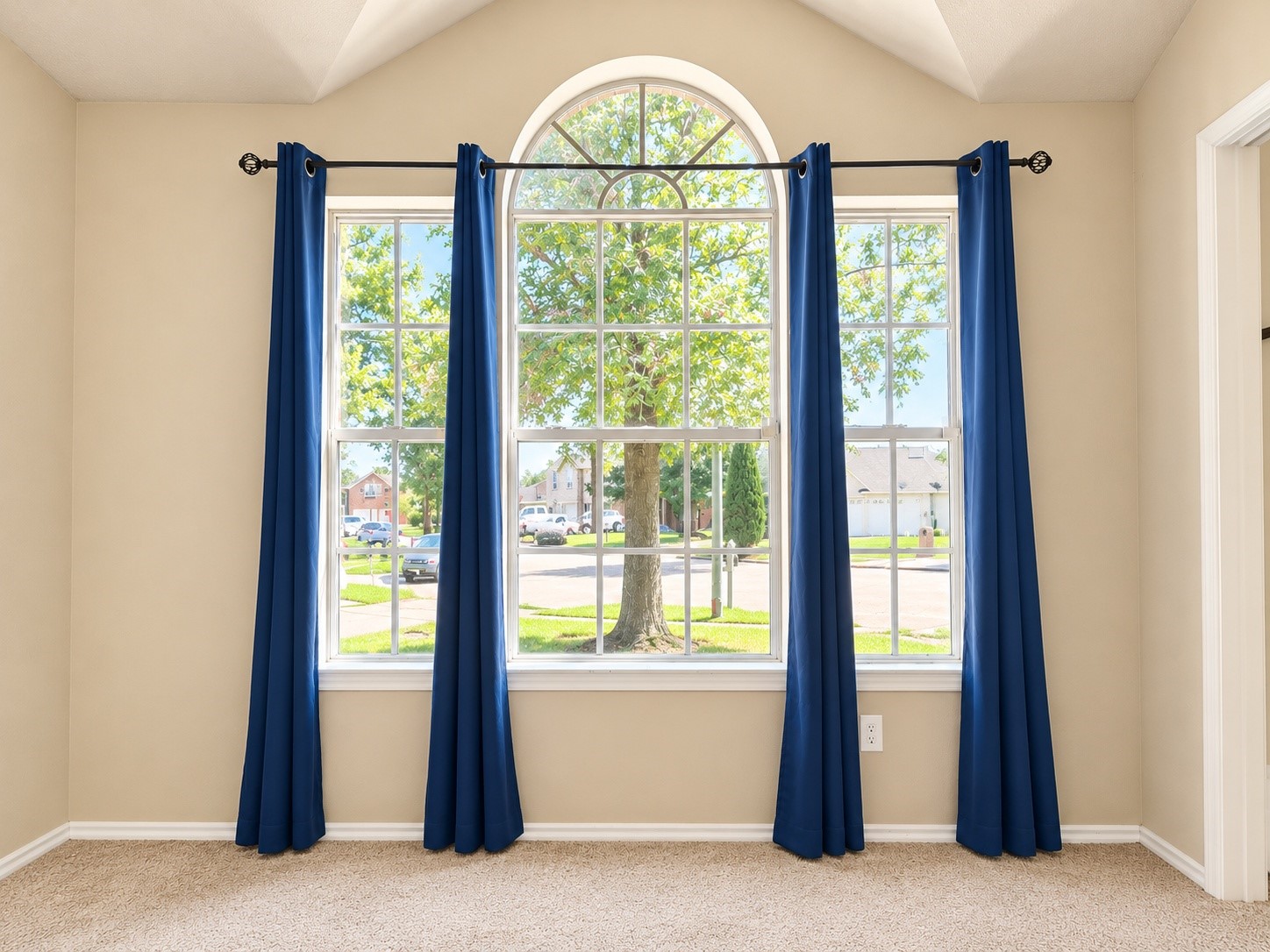 Second bedroom features a beautiful arched window, abundant natural light, and views of the tree-lined neighborhood.