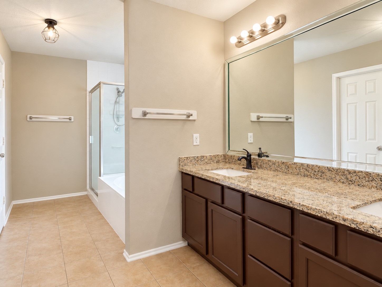 Primary on-suite bathroom with two sink vanity and granite counter top that matches the kitchen and second bath countertops.
